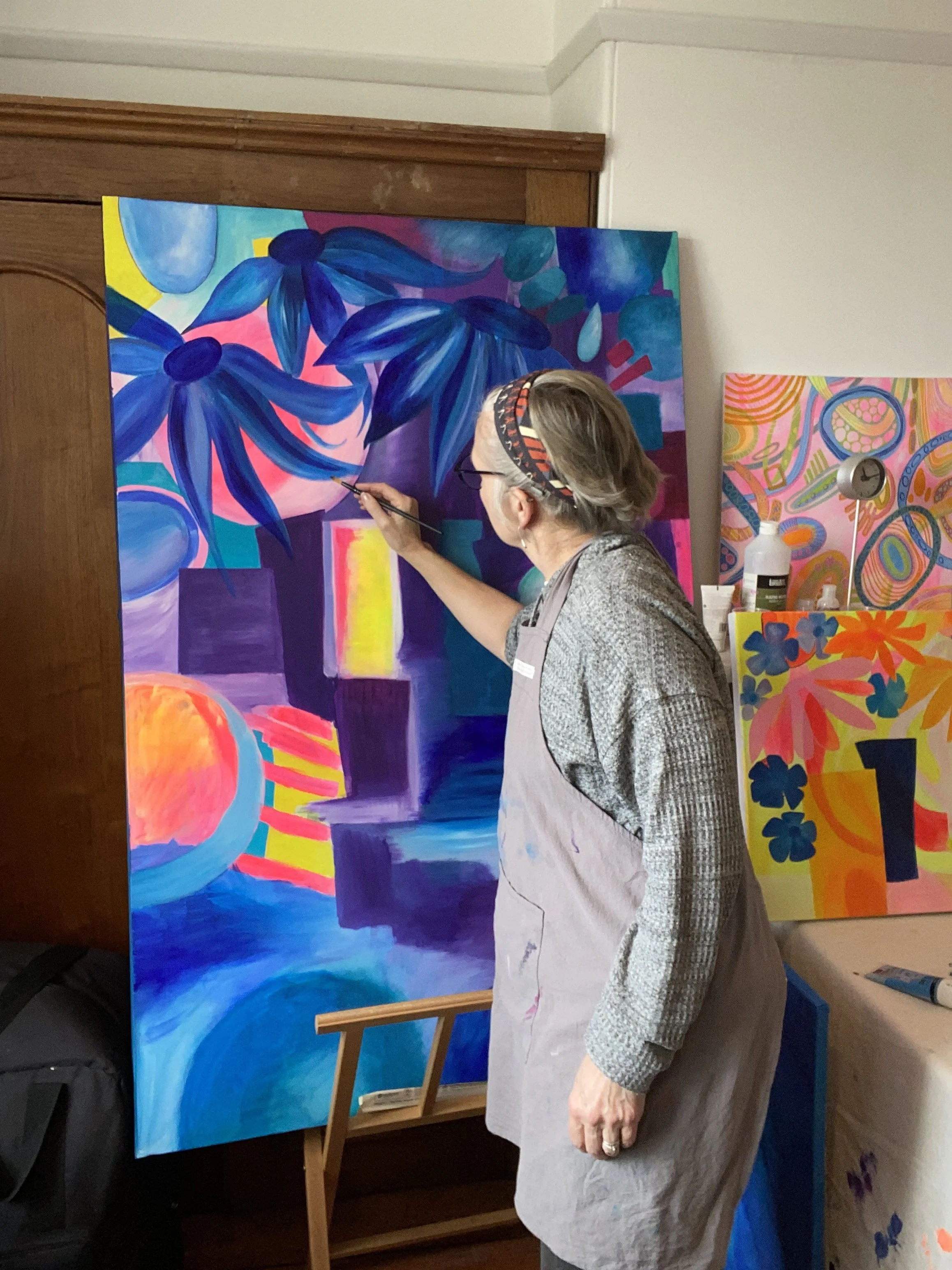 Cate Field painting a large colourful canvas in her studio