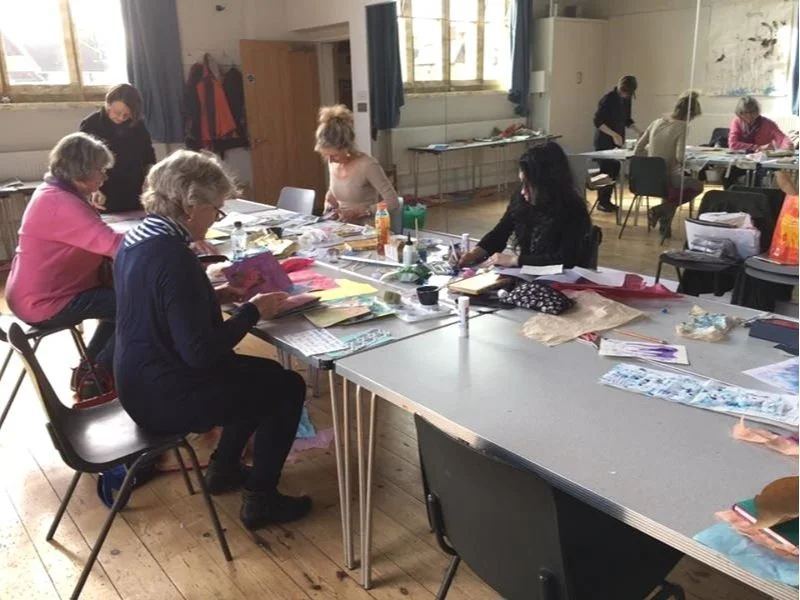 Women creating together around tables at a Cate Field art workshop