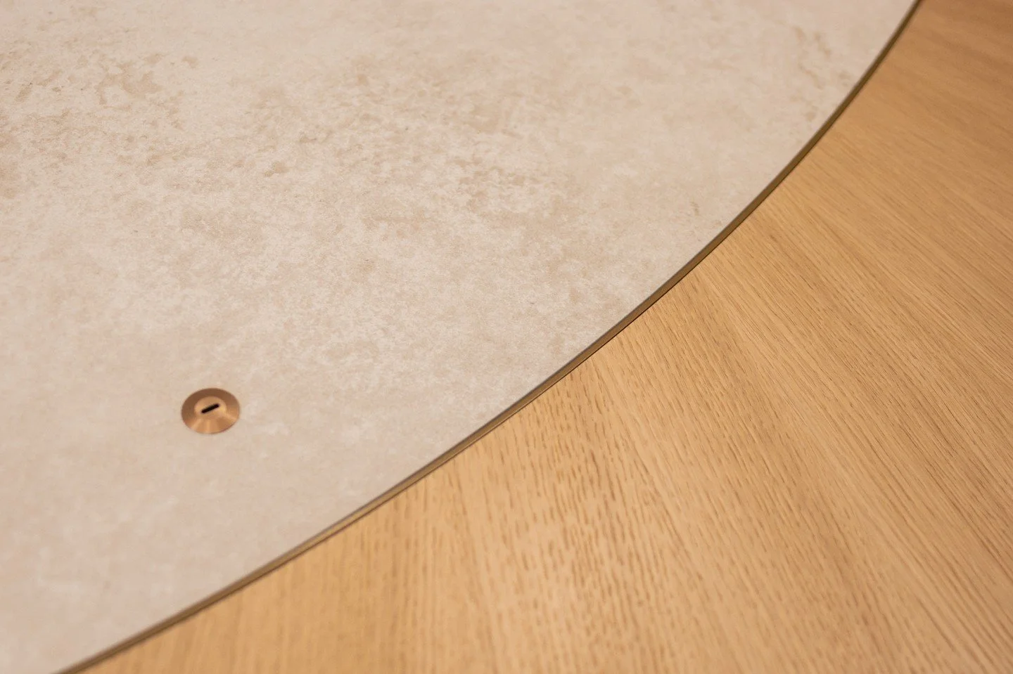 A detail from a recent project: a bespoke meeting table crafted for a London-based financial company. Featuring a freestanding oak radial veneer top with a stone centre, rose gold USB-C socket, and powder-coated steel base with discreet access doors 