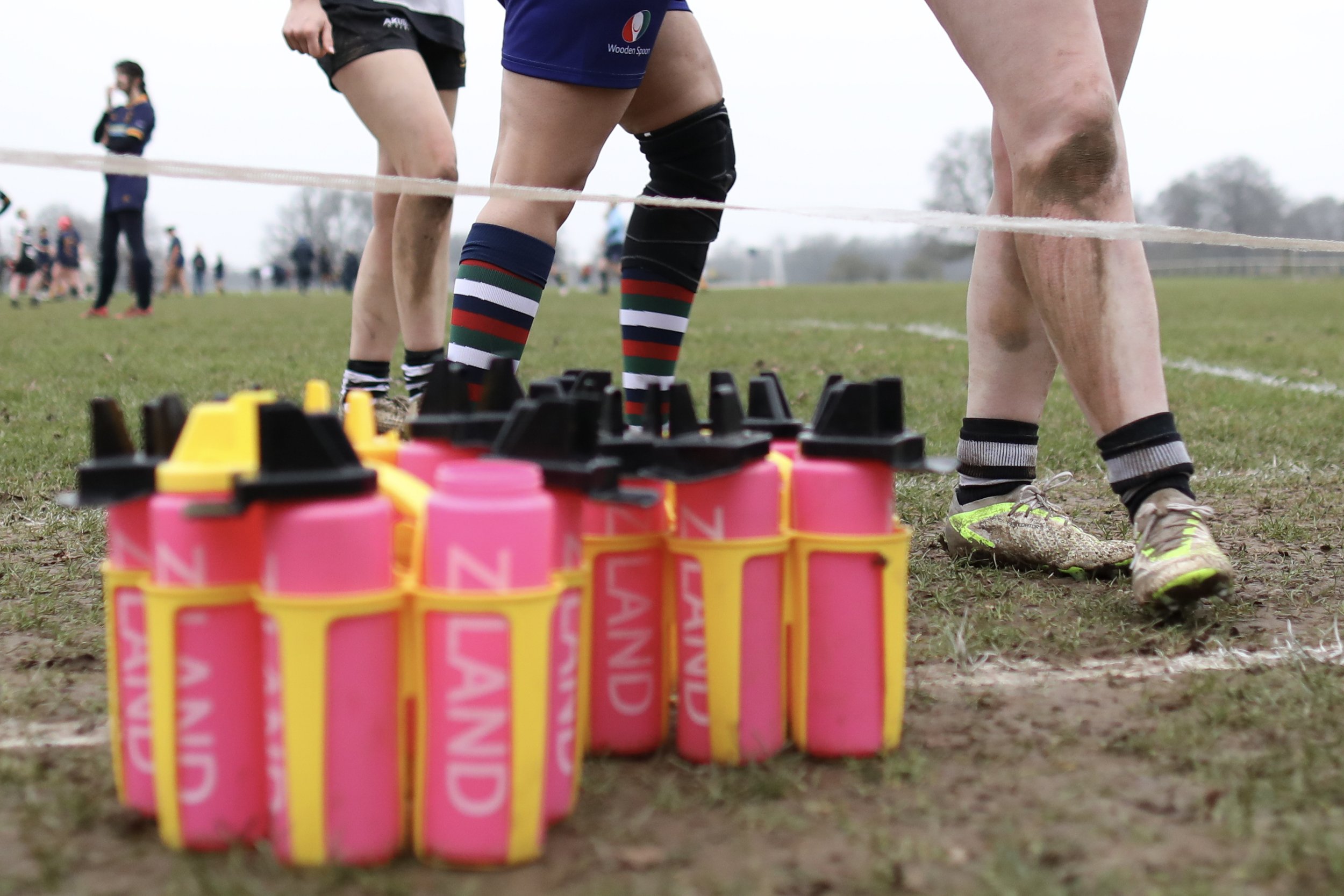 A rugby player preparing for a match, with pink antiseptic bottles lined up on the ground in front of him.