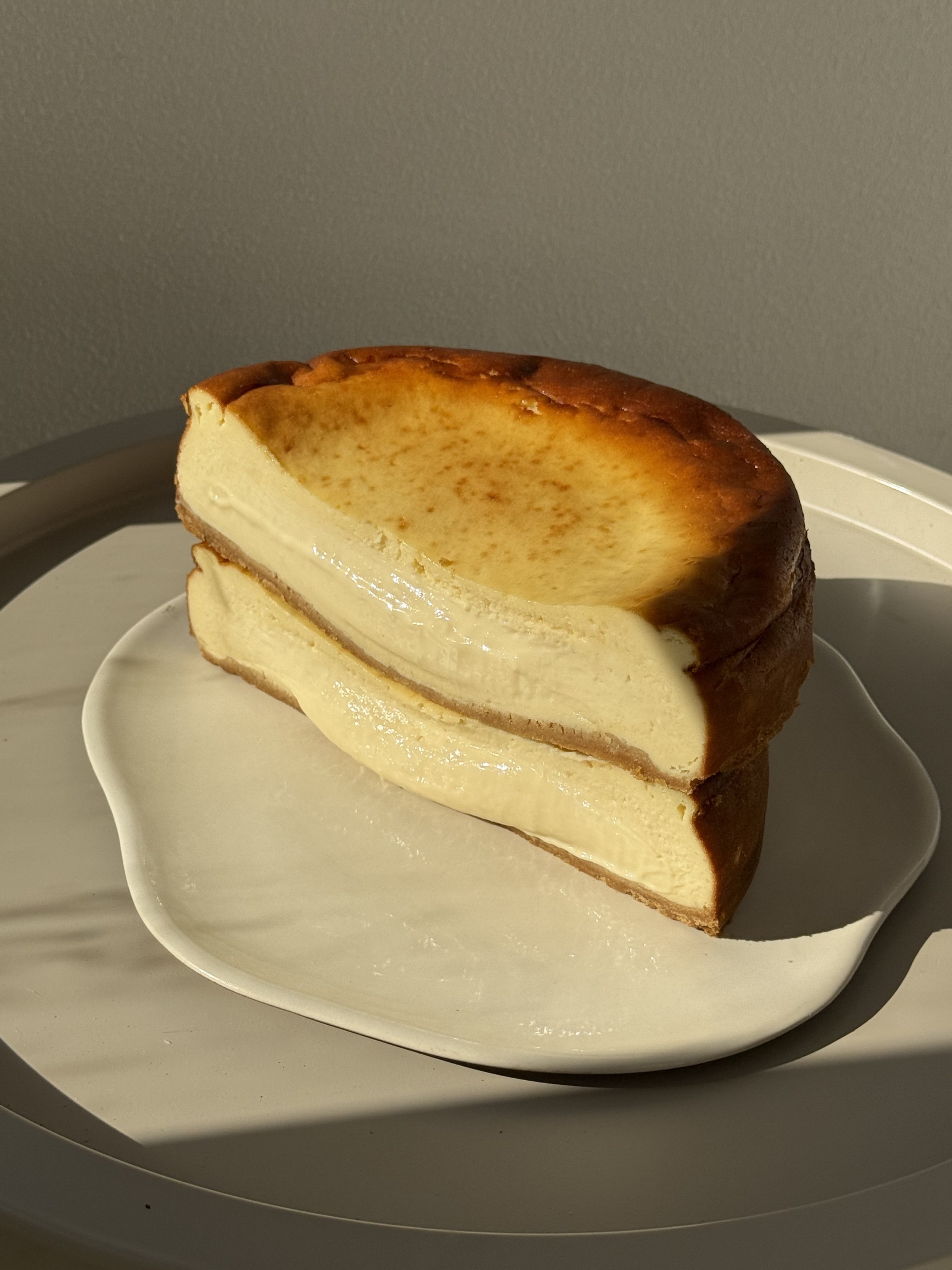 Half of a cheesecake with a golden brown top on a white plate