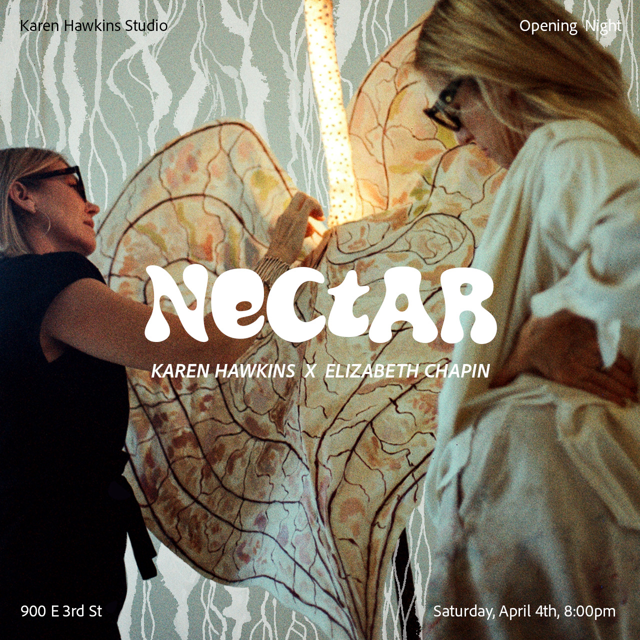 Colorful illuminated artificial flowers and plants arranged indoors, with a paper or fabric mobile hanging on the wall behind them.