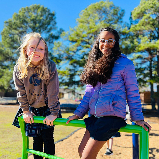 Two students smiling on the playground at Christ Little Rock School, showing the welcoming Christian community and joyful environment families experience when visiting campus.