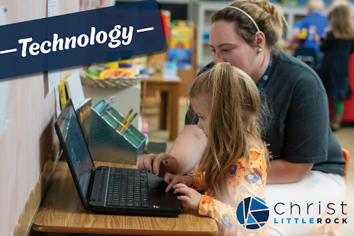 Young student using a laptop with teacher support at Christ Little Rock School