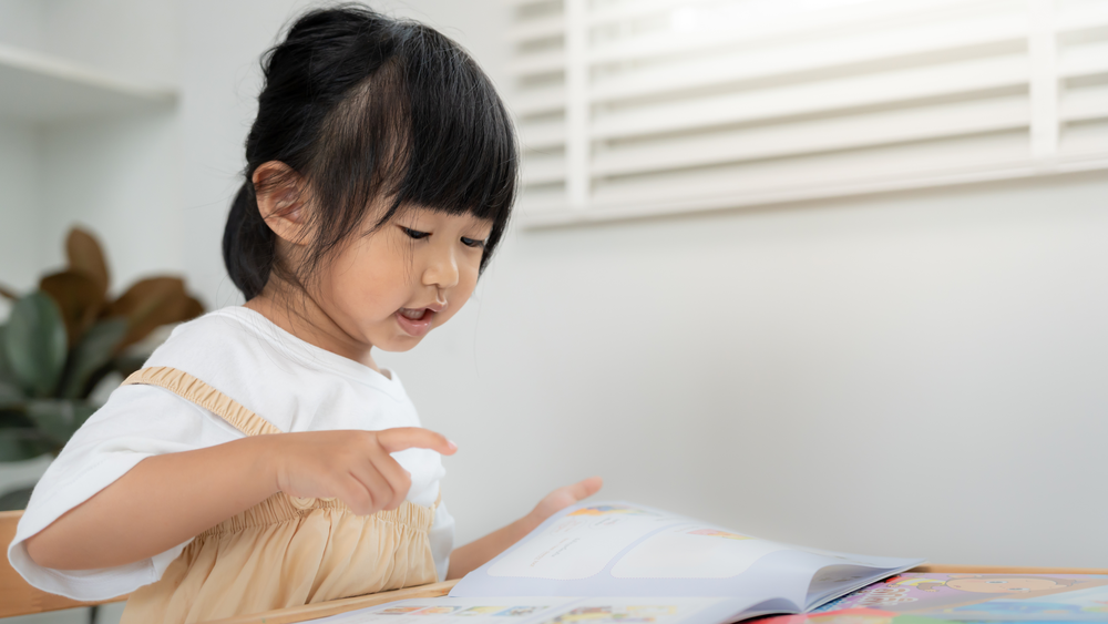 Young child building reading skills through early learning activities before kindergarten at Christ Little Rock School.