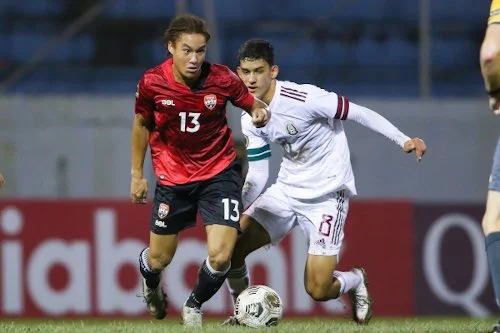 Two soccer players competing for the ball during a match. One wears a red jersey, the other a white jersey. Both players are focused on the ball on the field.