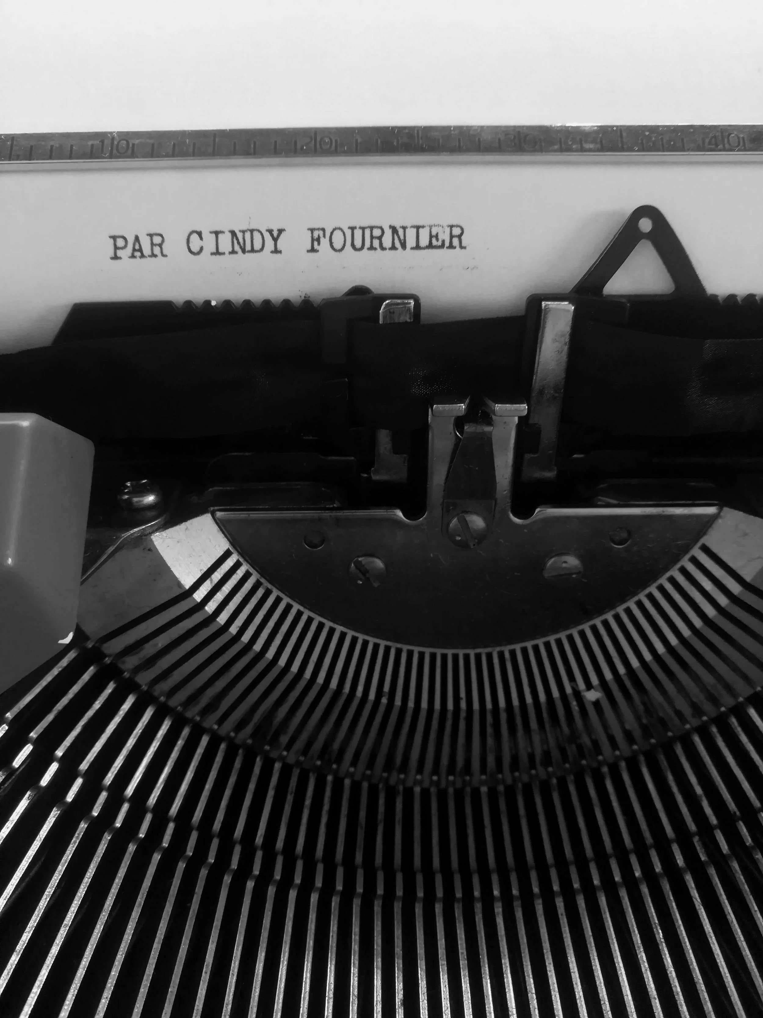 Close-up of a typewriter with the name 'Par Cindy Fournier' typed on the paper.