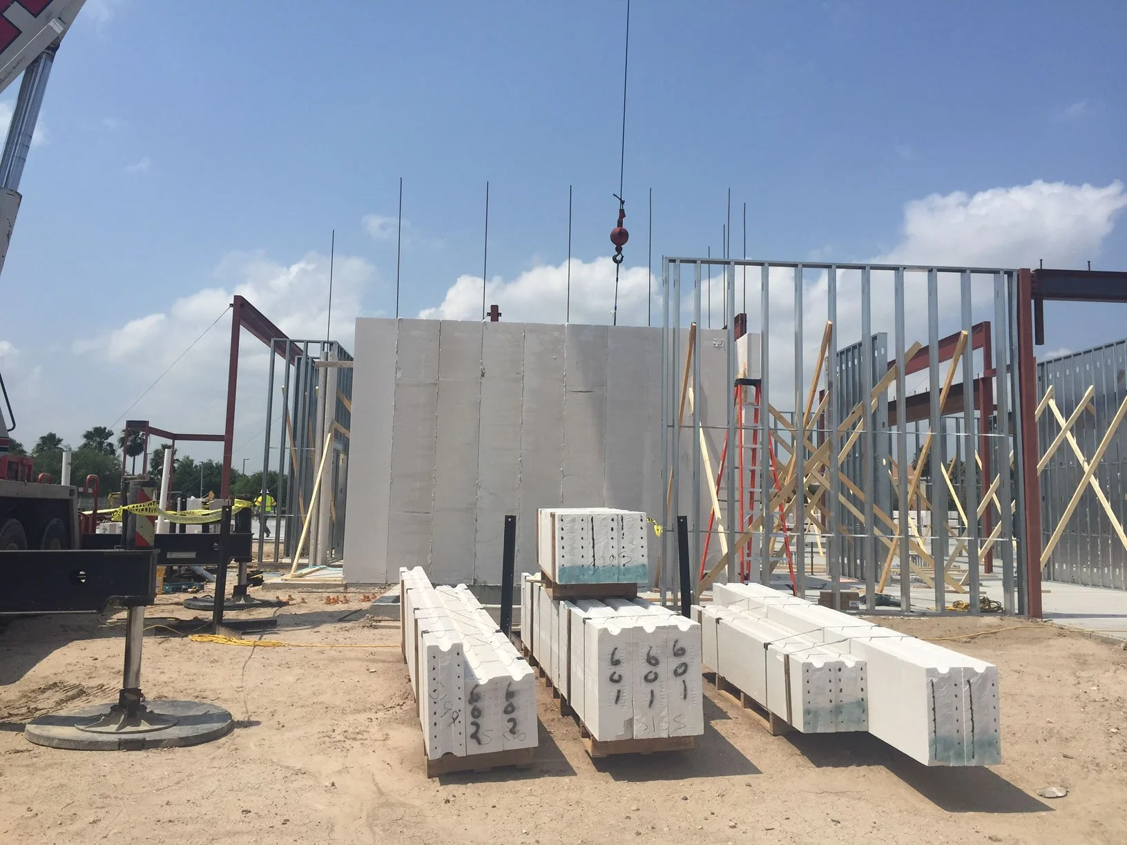 Building construction site with steel framing, concrete blocks, and building materials.