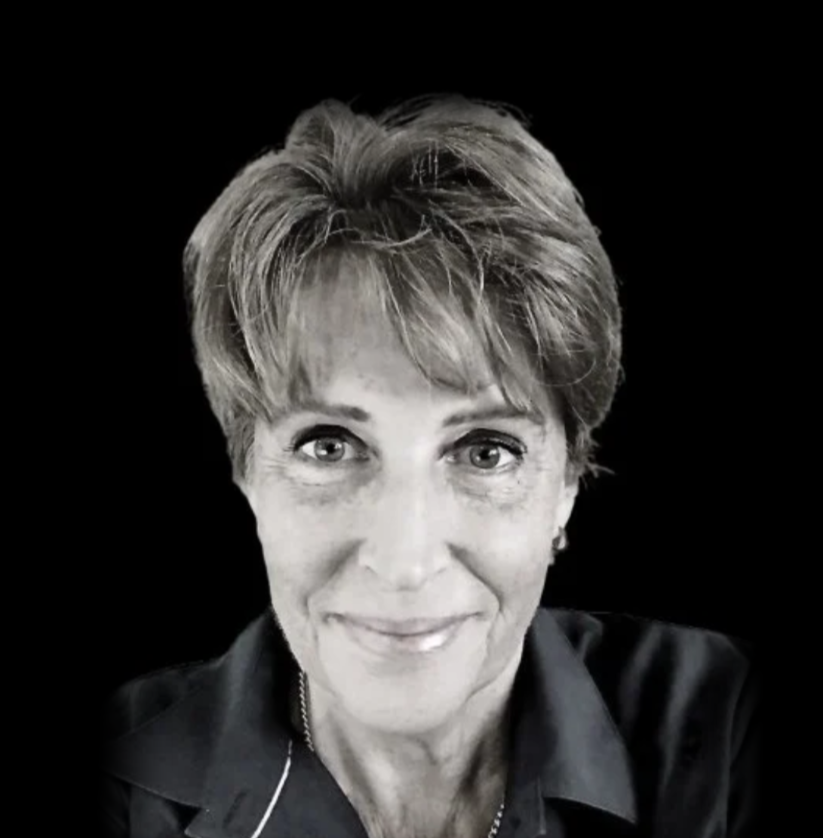 Black and white portrait of a woman smiling with short hair and a collared shirt.