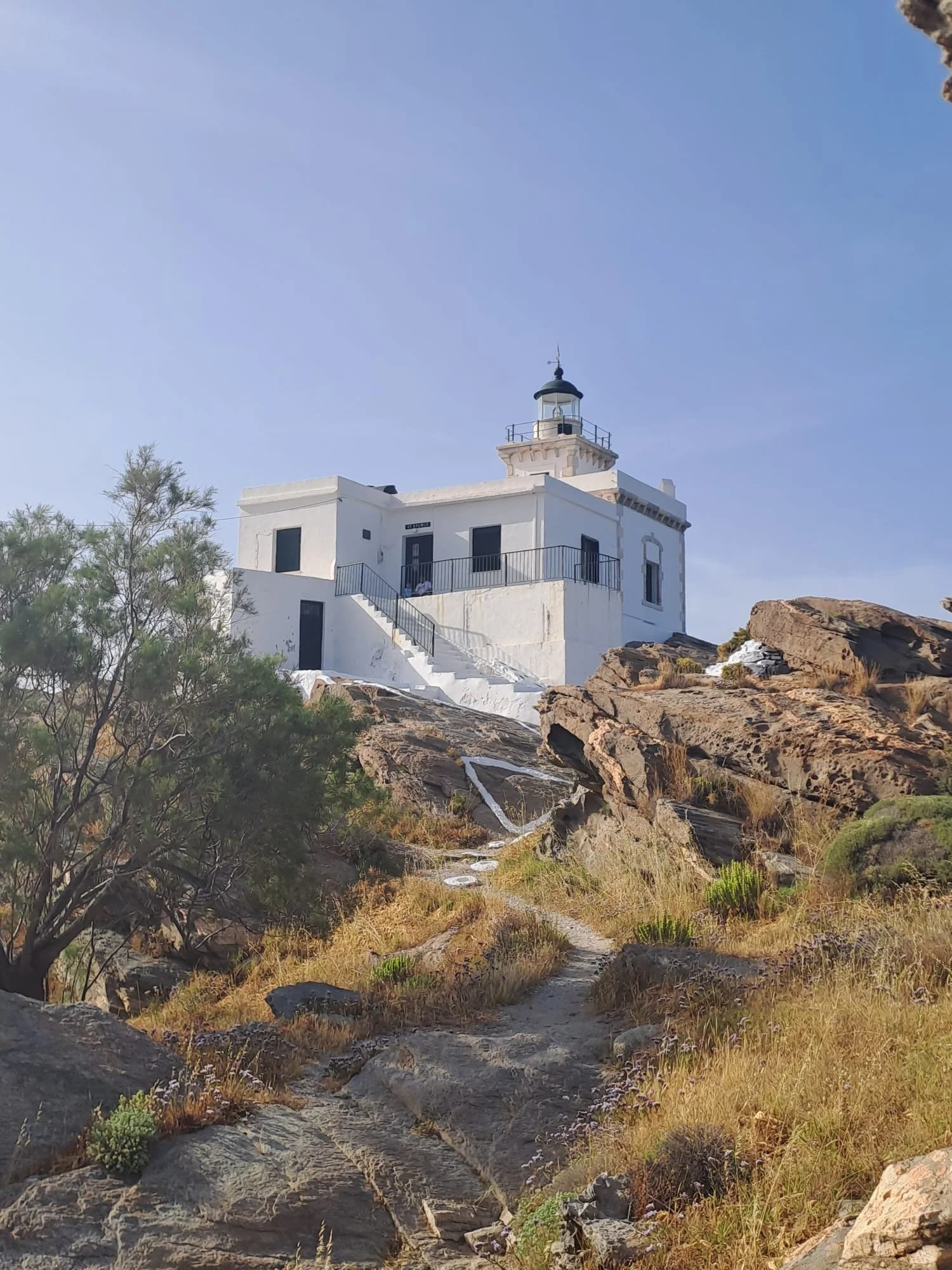 white building Korakas lighthouse on top of rocks in Paros Greece