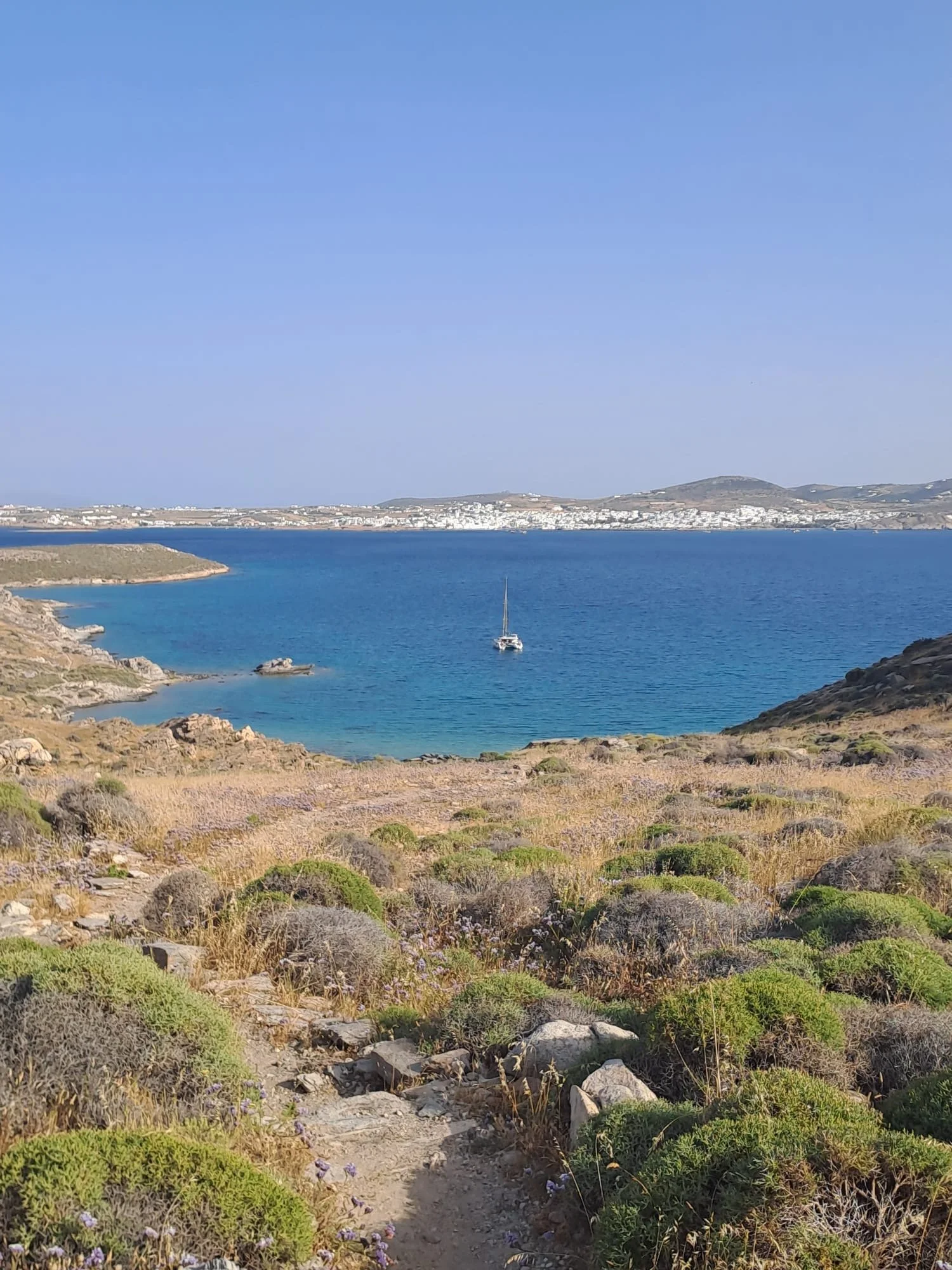 View from Korakas lighthouse on Paros Greece of blue water in the bay with one sailboat