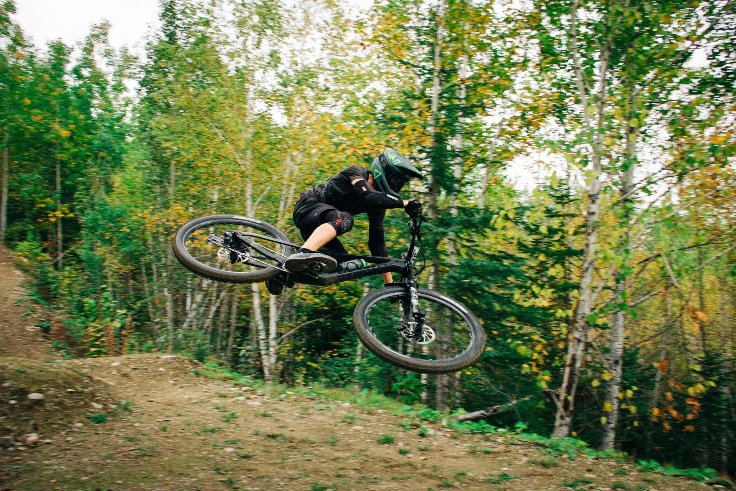 Cycliste faisant un saut sur un VTT dans une forêt.