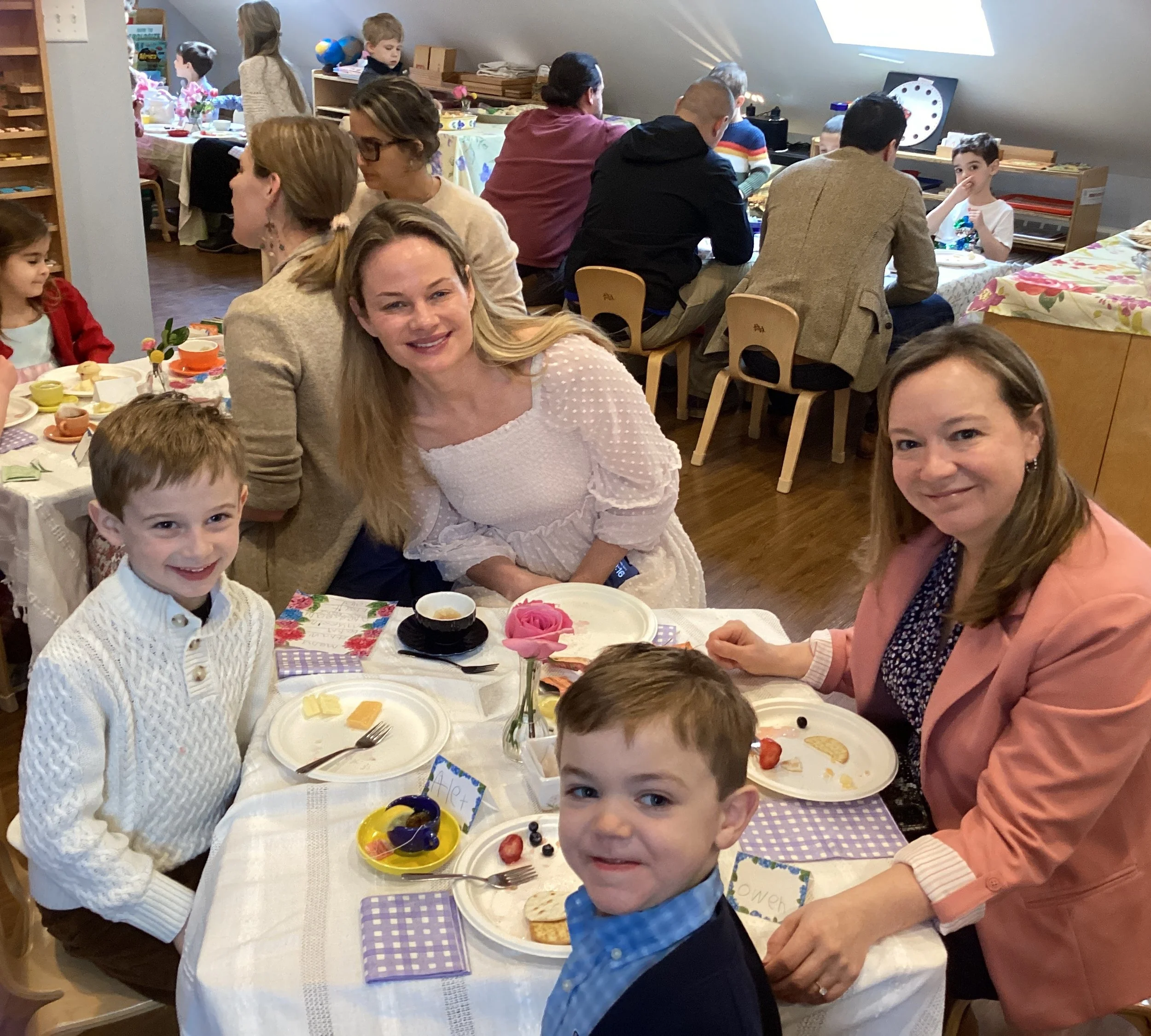 Children and adults celebrating Spring Tea in a cozy room.