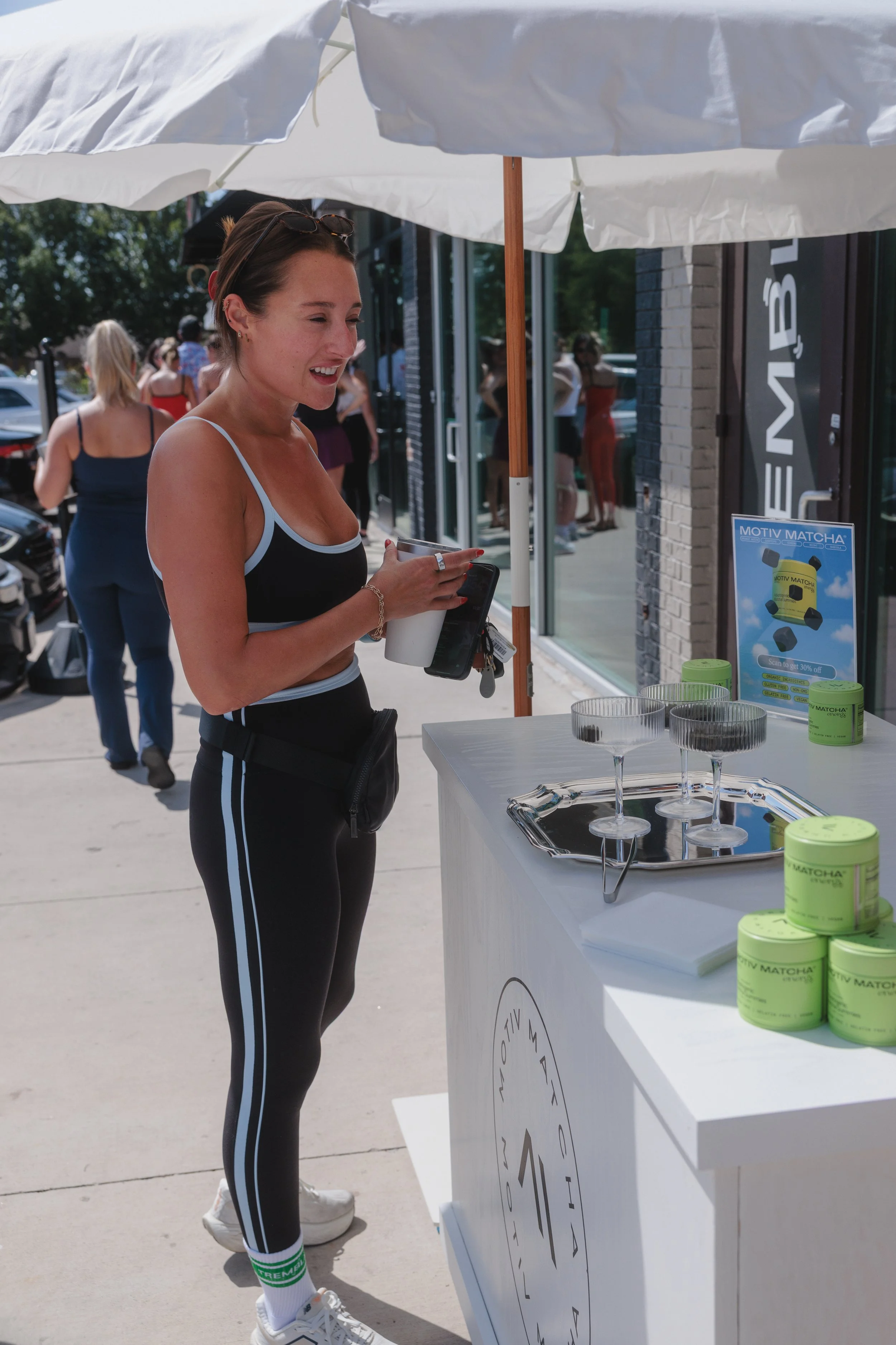 A millennial woman sampling CPG brand products at a storefront retail activation.