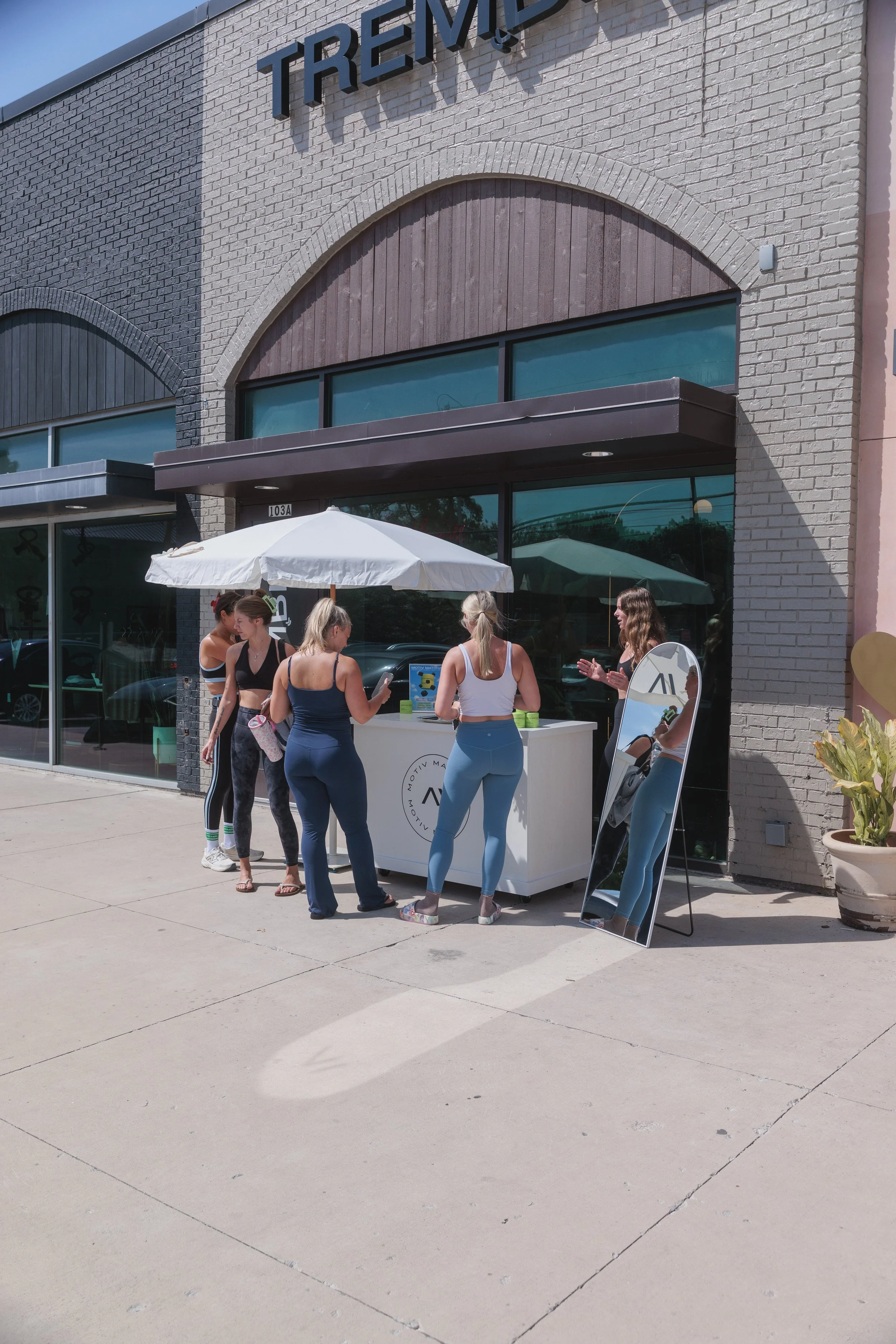 A group of passerby people stopping by a storefront brand collaboration activation to learn about the business and the CPG brand.