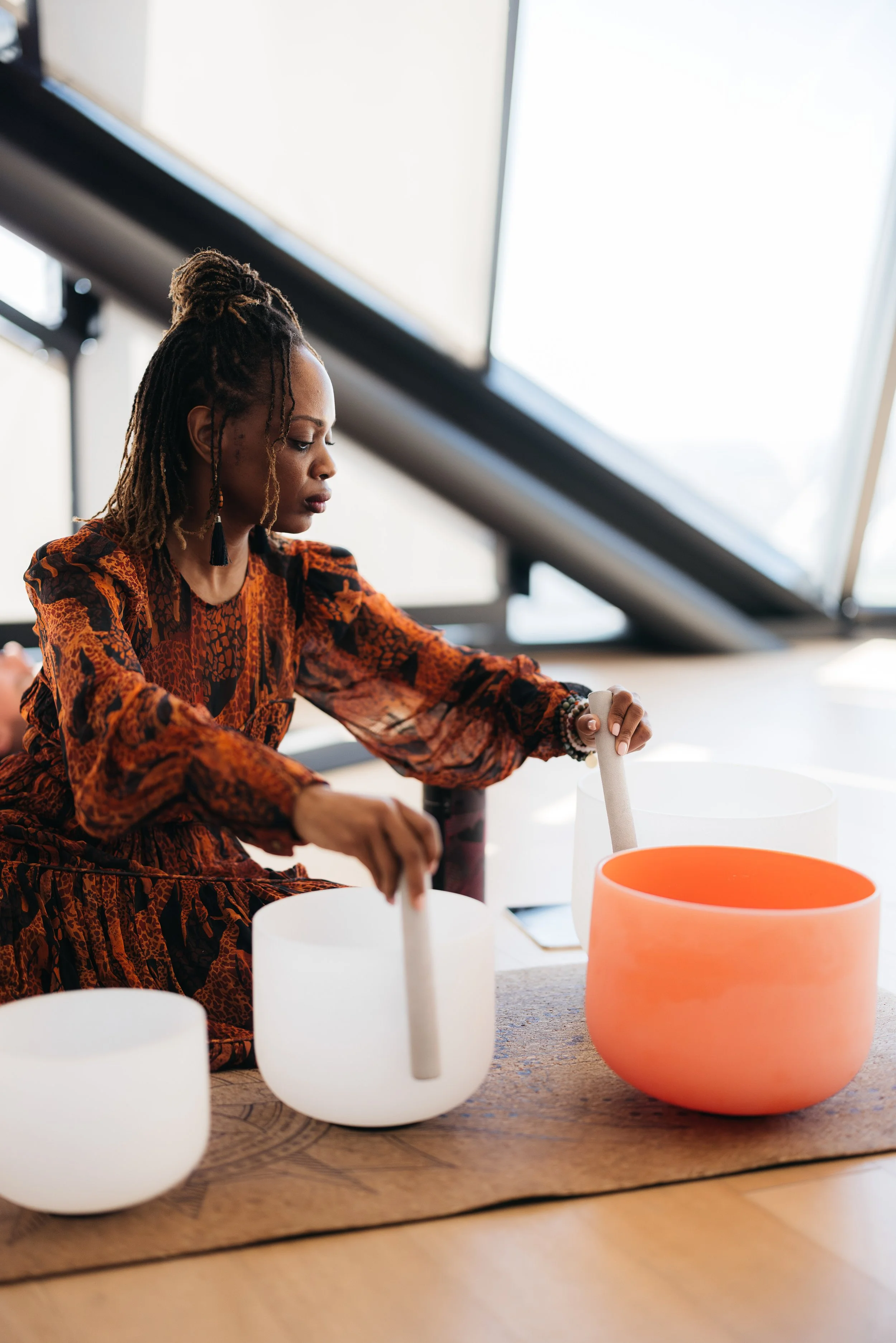 Sound bath practitioner from Sanctum Med + Wellness interacting with singing bowls.
