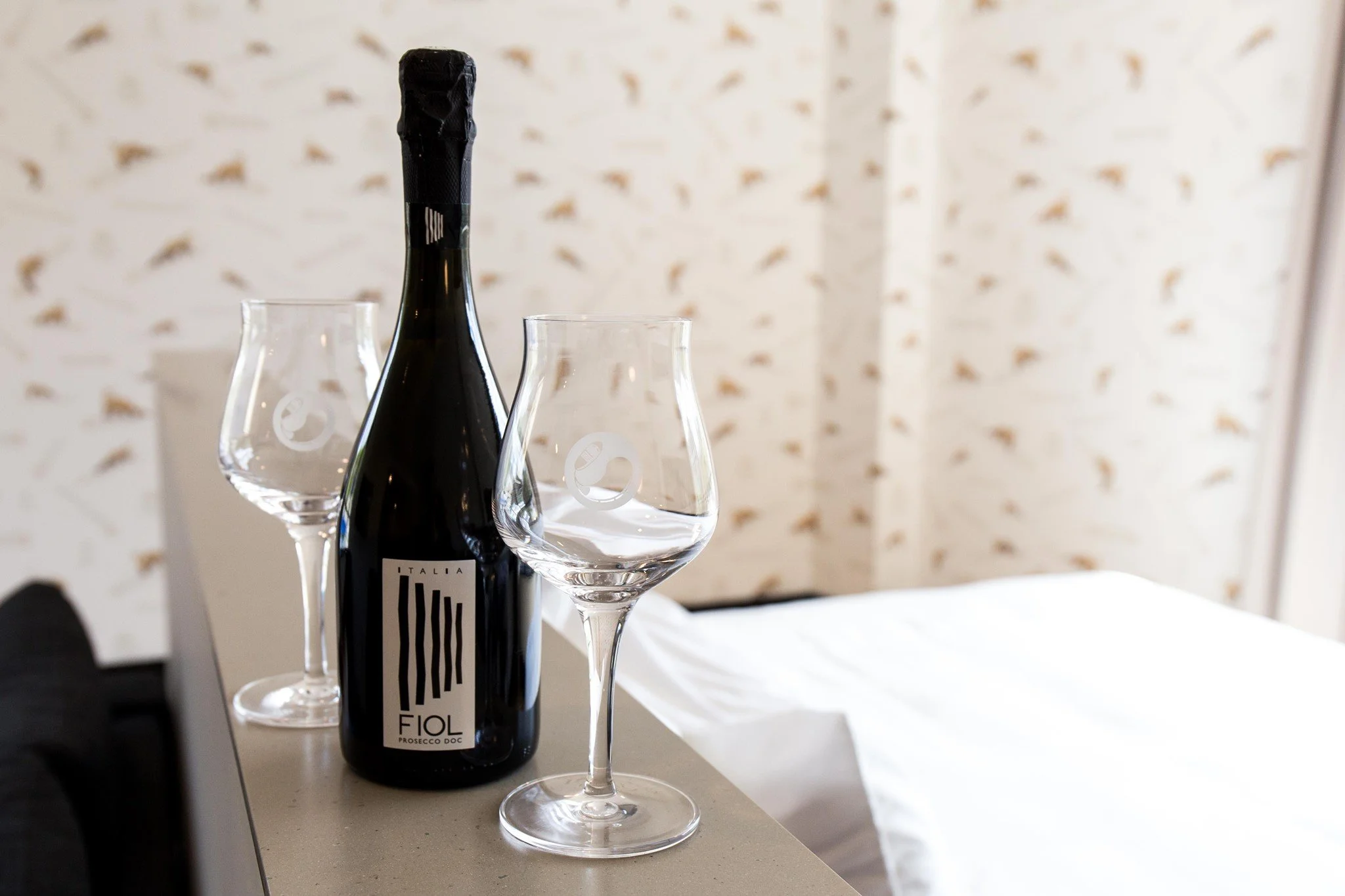 Bottle of Fiol Prosecco with two wine glasses on a countertop.