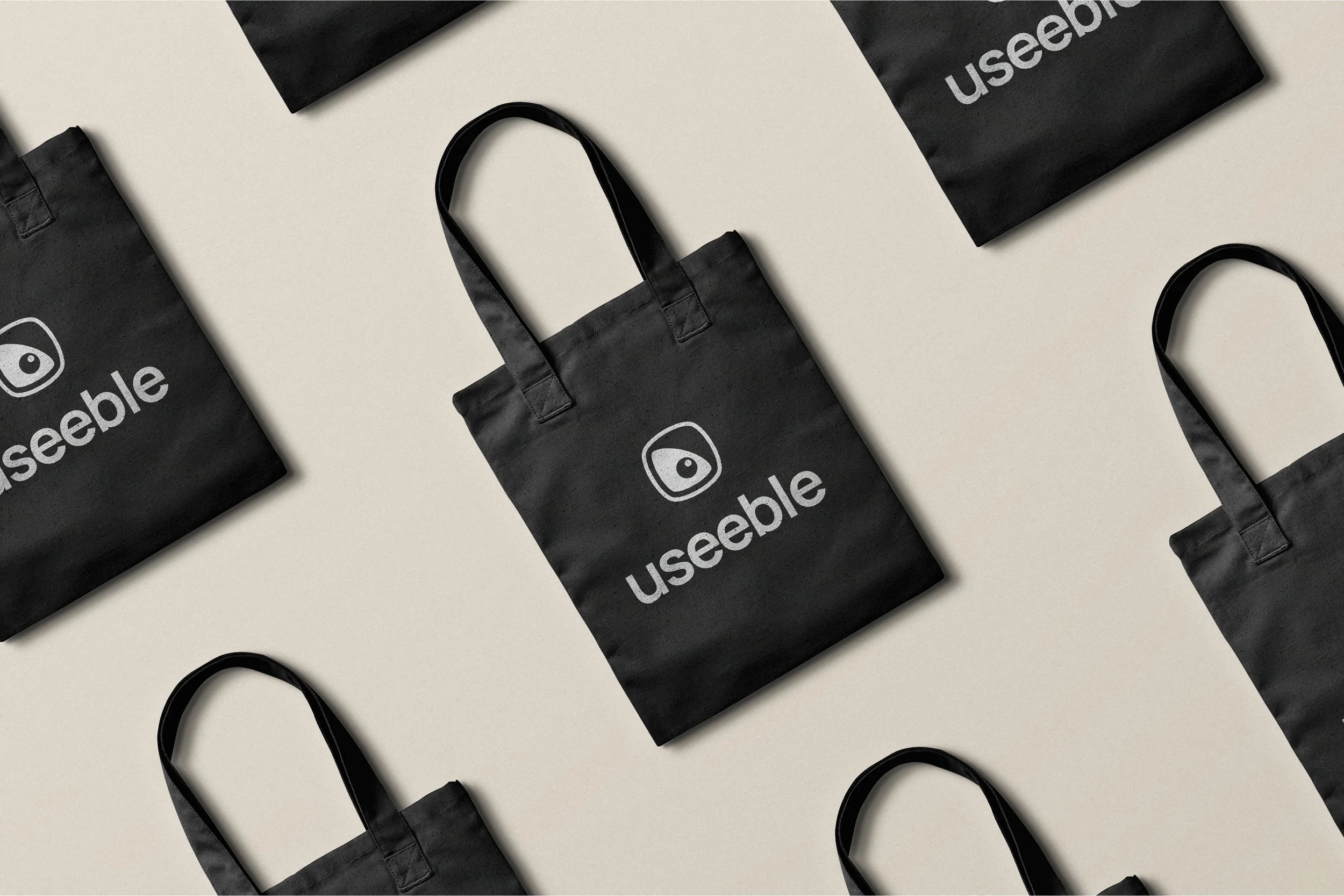 Black reusable tote bags with the 'useebl' logo in white, arranged on a light-colored surface.