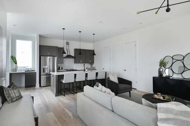 Open living area with a view of the sleek kitchen, showcasing modern design and furnishings in a Chestnut Hill townhouse for rent.