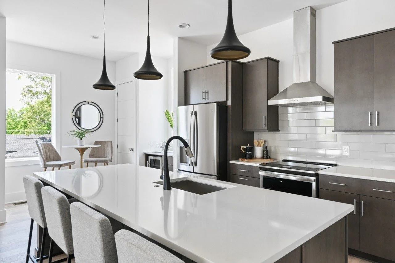 Modern kitchen with stainless steel appliances, island seating, and elegant pendant lighting in a Chestnut Hill townhouse for rent