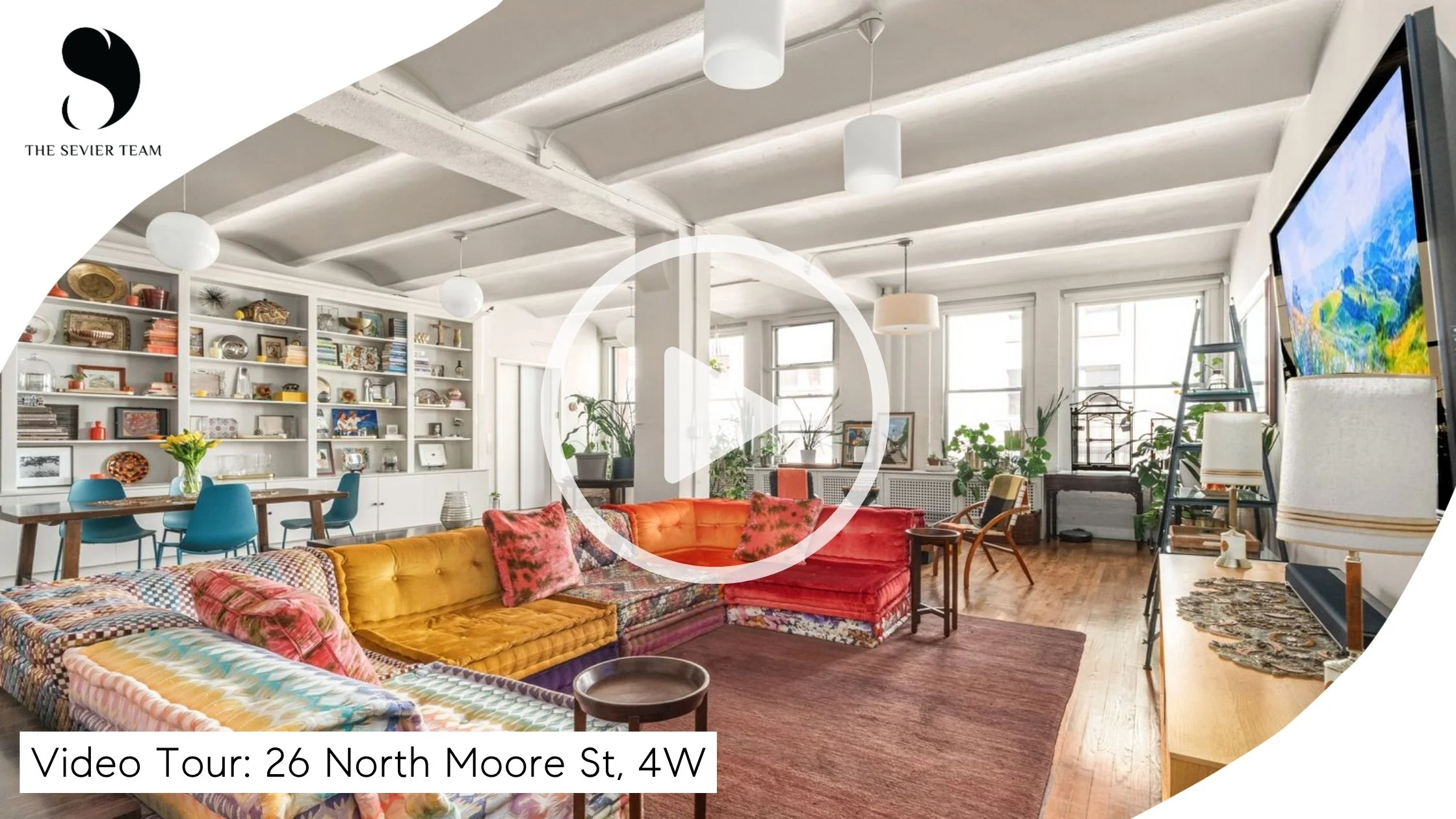 A spacious, well-lit living room with colorful furniture including a yellow sofa and a red sofa, a large flat-screen TV, a wooden dining table with teal chairs, white built-in shelves with decor and books, numerous potted plants, large windows, and ceiling lights.