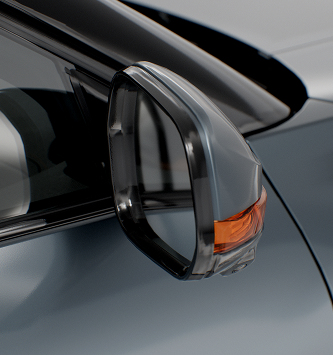 Close-up of a side mirror on a modern car with a black frame and an orange turn signal indicator.