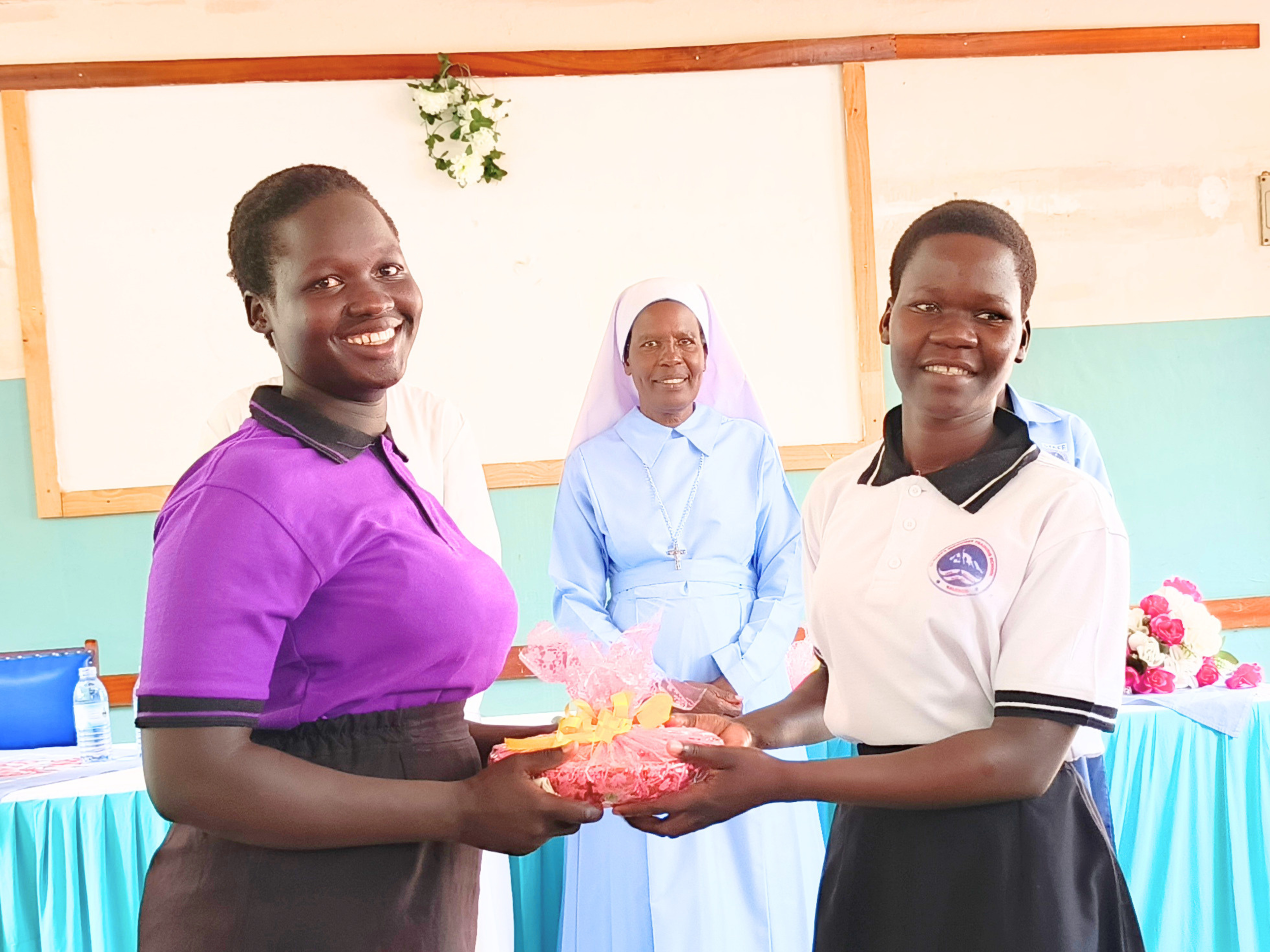 Outgoing leader in purple Tshirt receiving a gift from an incoming leader