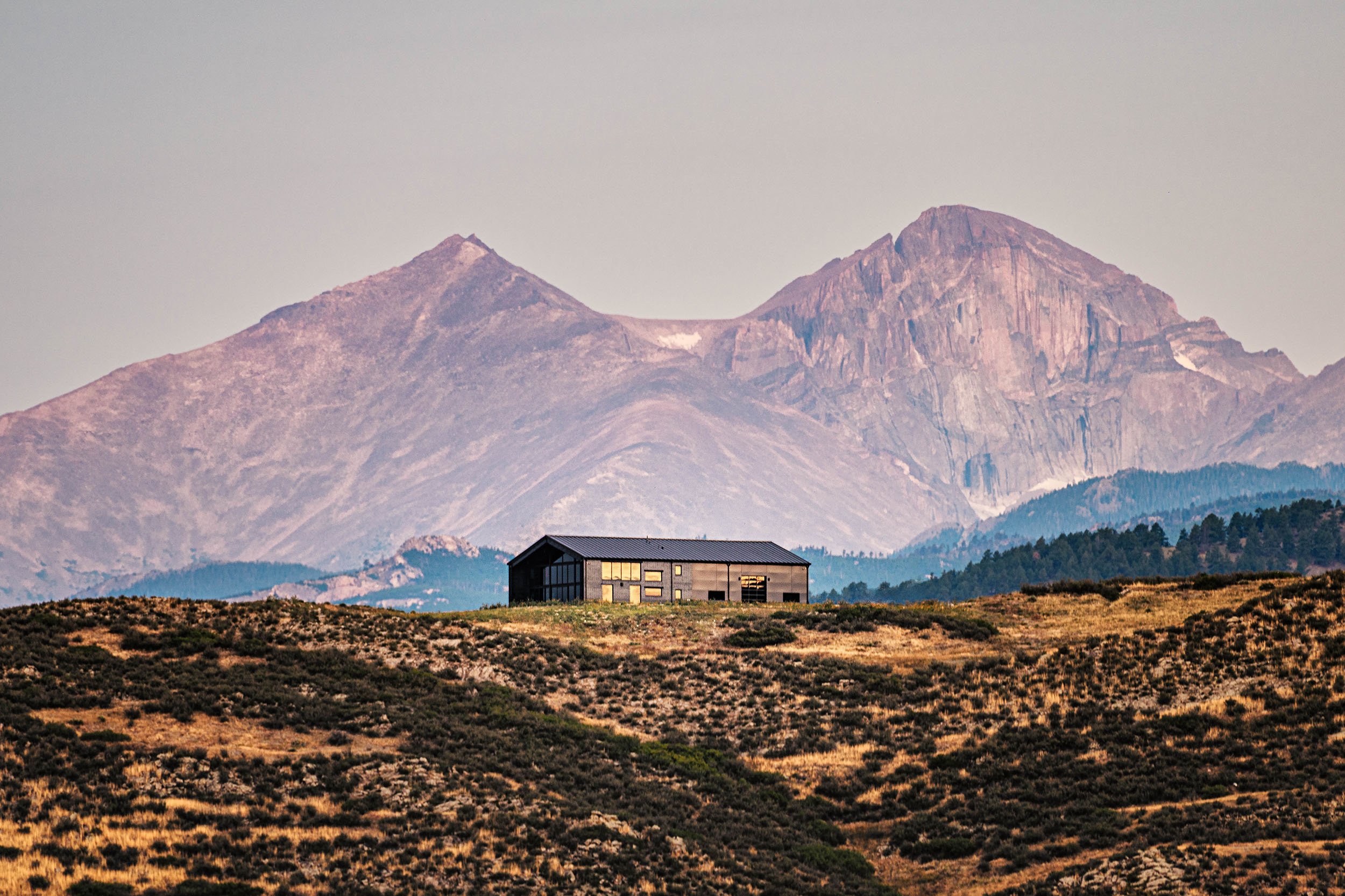 Industrial modern home with black metal siding and a metal roof on a hillside in Loveland, Colorado