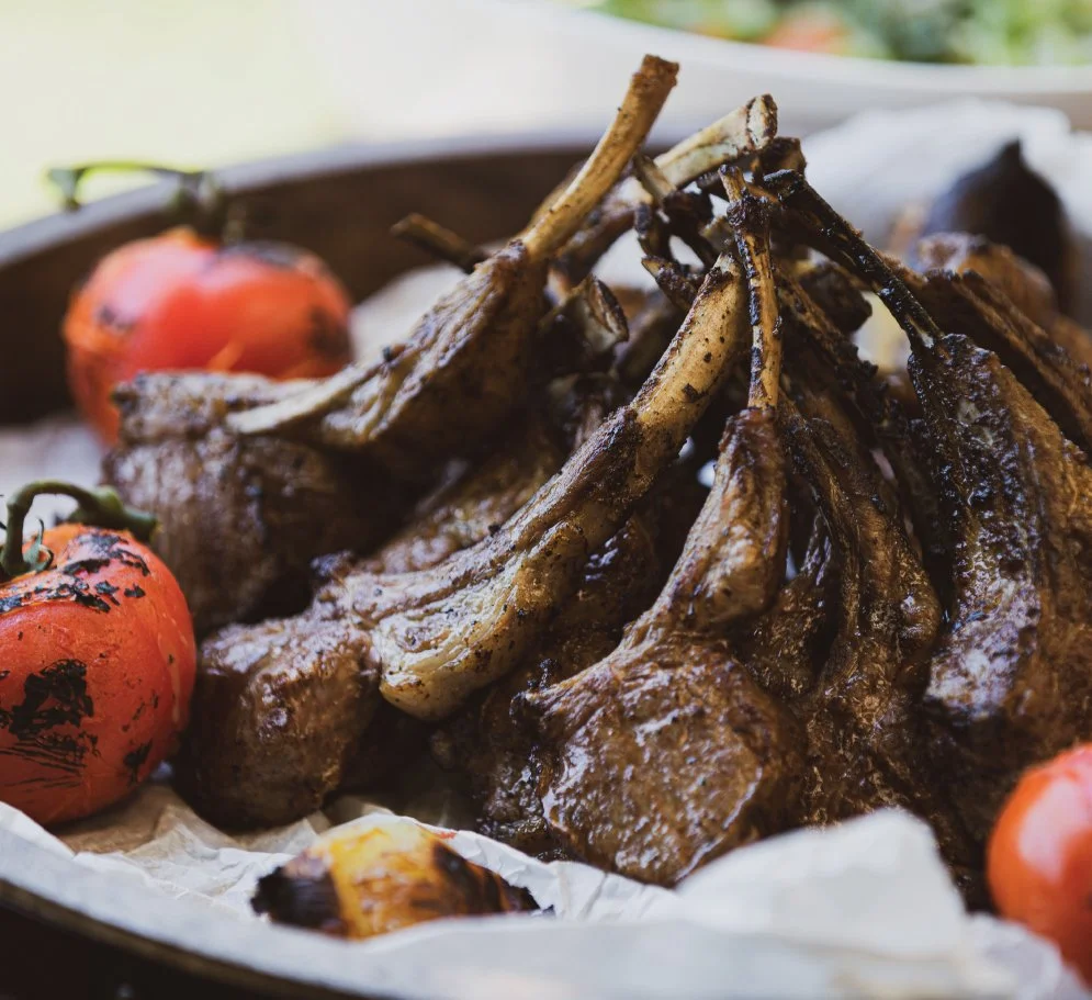 perfectly grilled lamb chops with charred tomatoes on a baking sheet