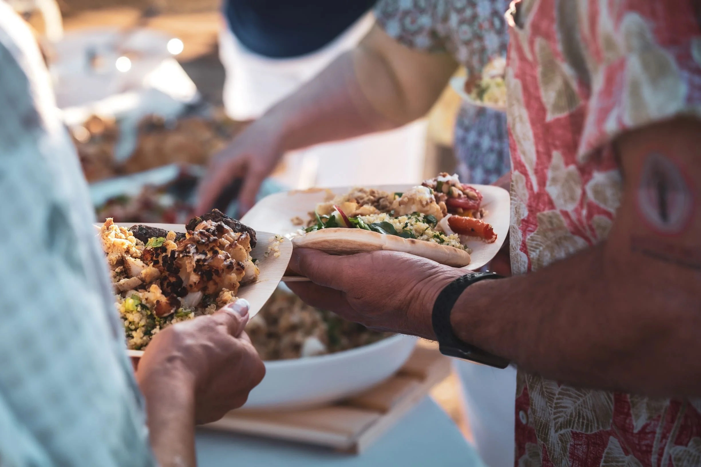 "Guests at a buffet of grilled meat, quinoa tabbouleh, and roasted vegetables at a San Diego catered event