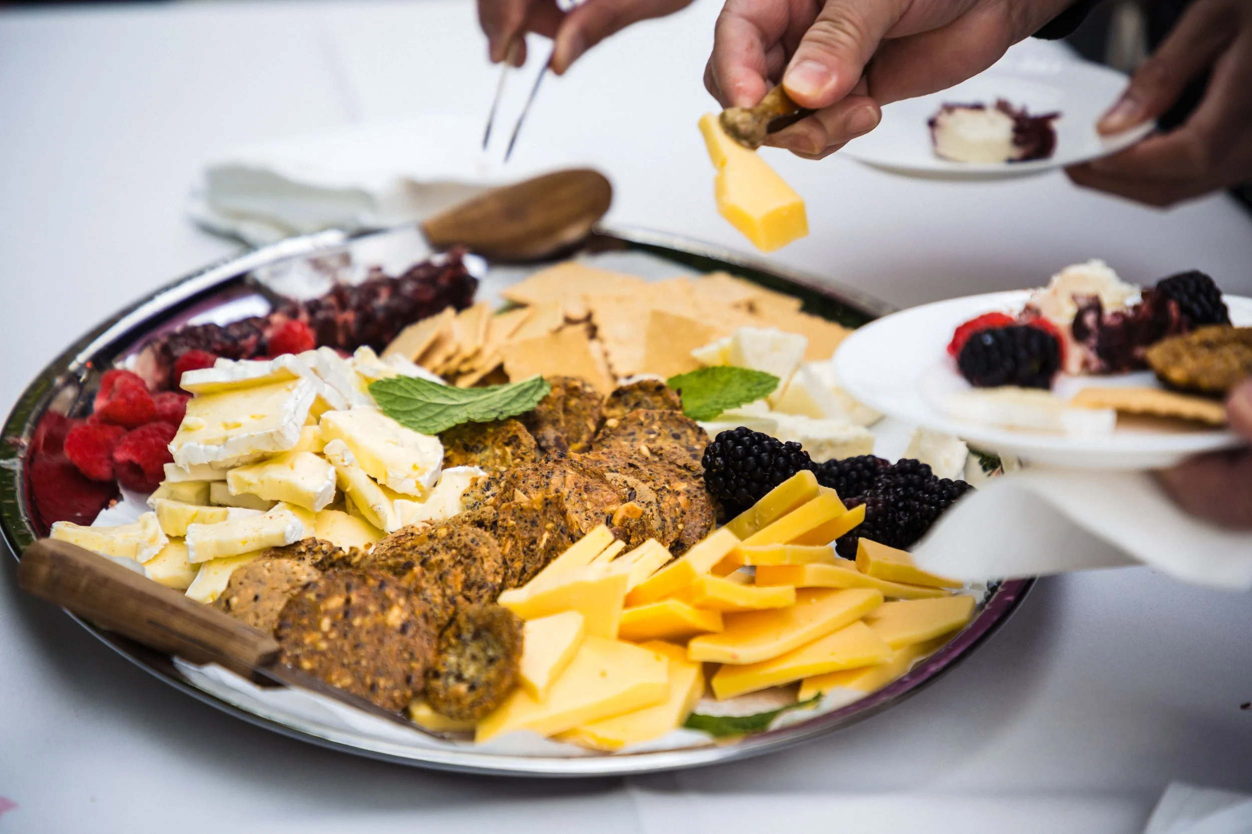 A cheese and meat charcuterie platter with assorted cheeses, meats, berries, and garnishes on a large serving tray.