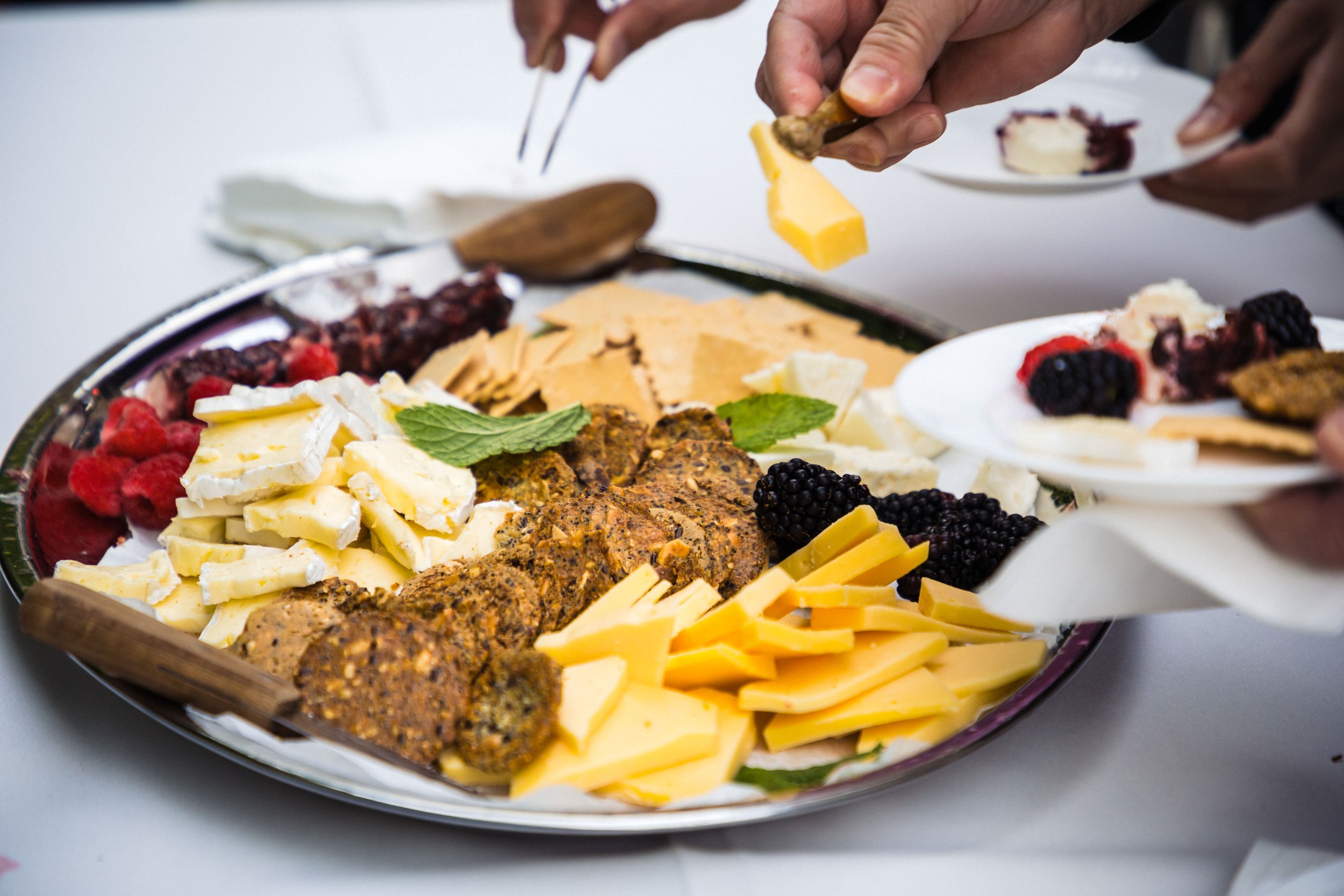 A cheese and meat charcuterie platter with assorted cheeses, meats, berries, and garnishes on a large serving tray.