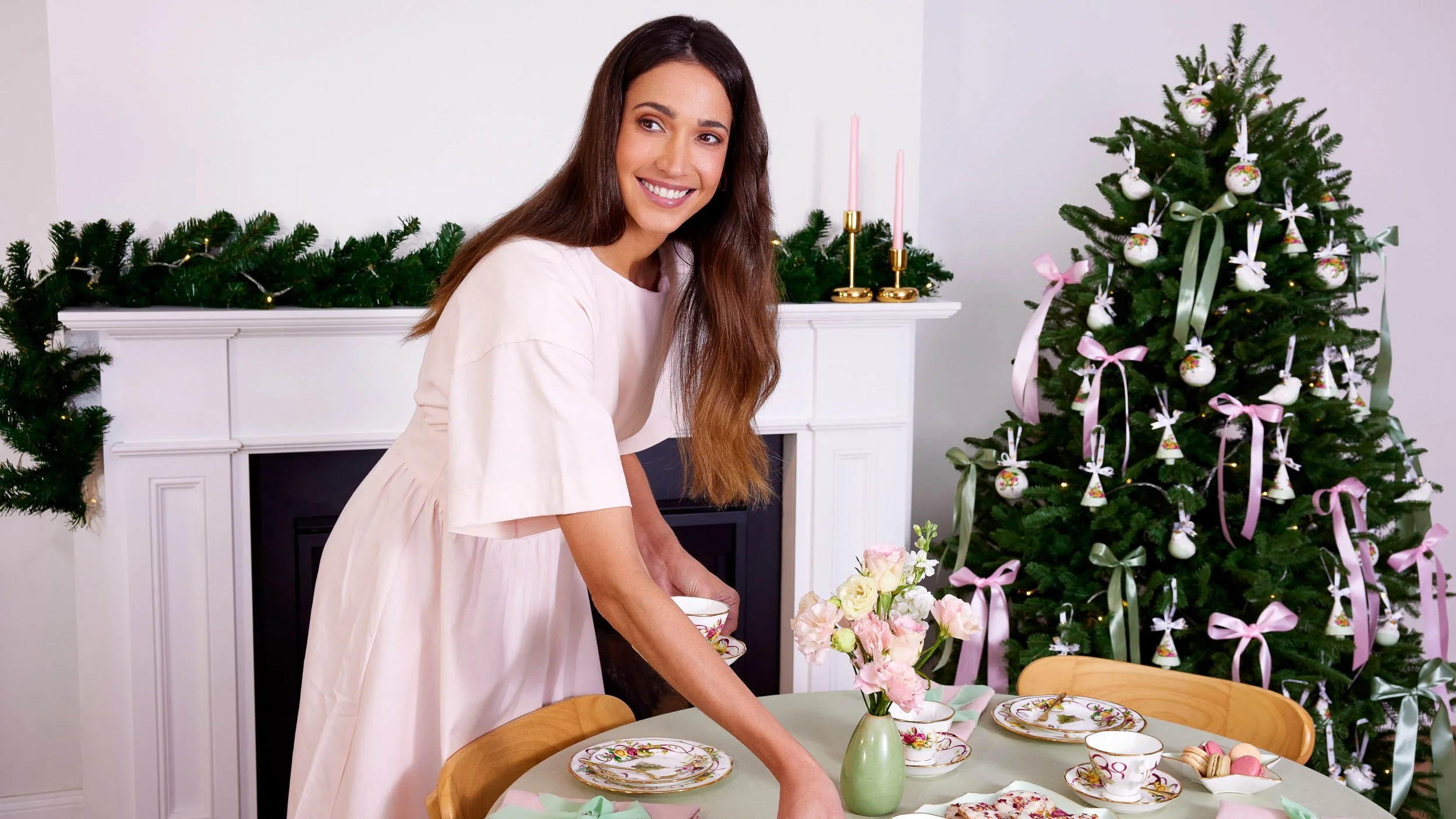 Royal Albert. Single female standing at table with a Christmas tree and fireplace behind her