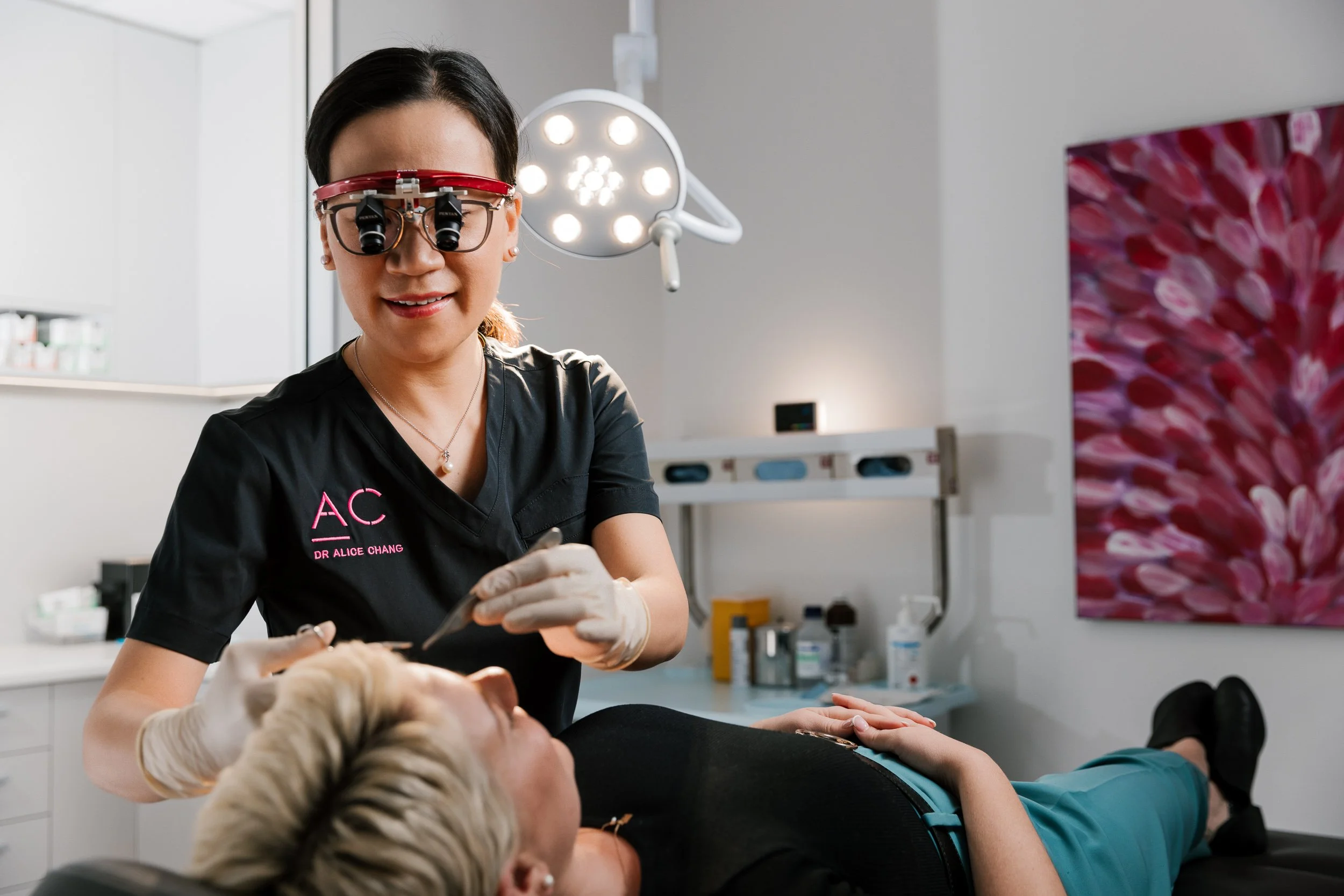 A female dentist with a magnifying headset examining a patient's teeth in a dental clinic.
