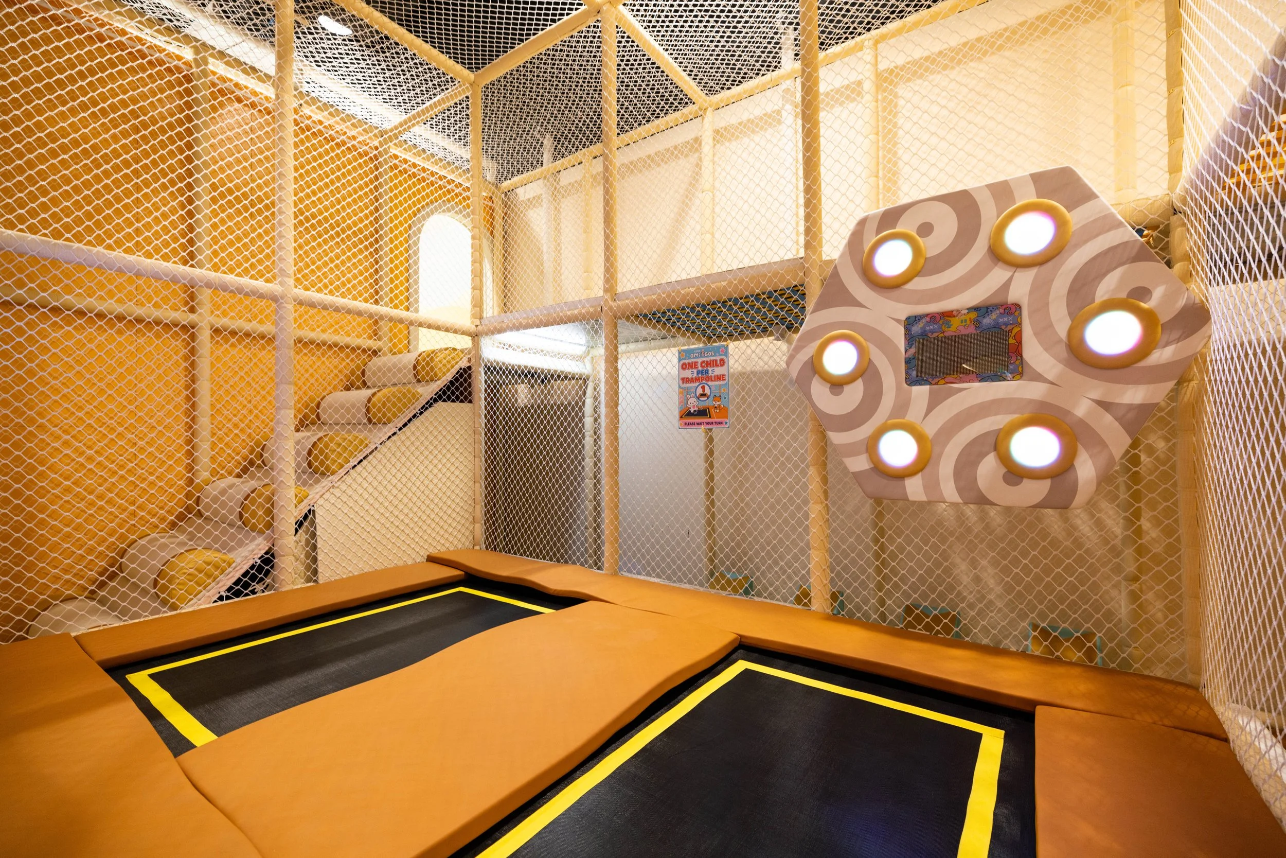 Children's indoor play area with ball pits, toys, and playful wall murals.