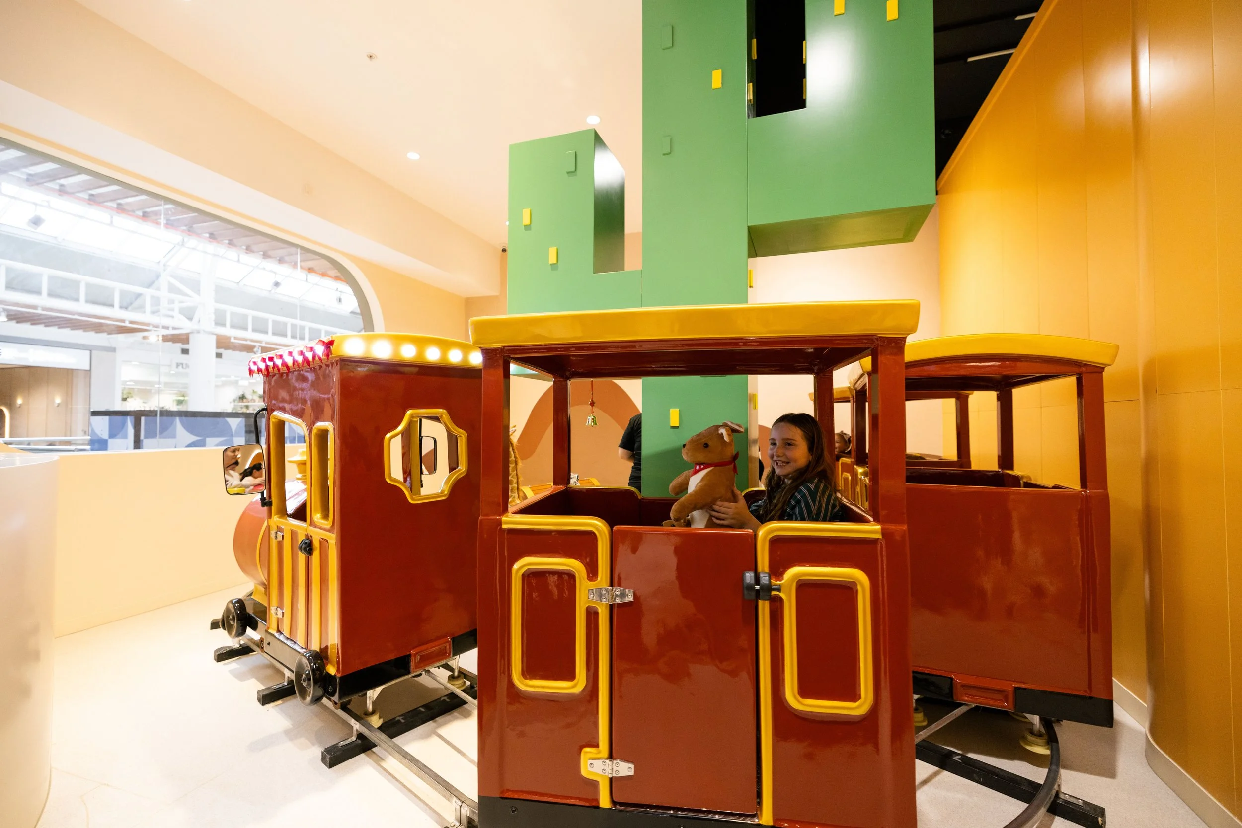 Red and gray toy fire truck playset with wood construction, picture of VIGA logo, and orange safety cones, inside a store.