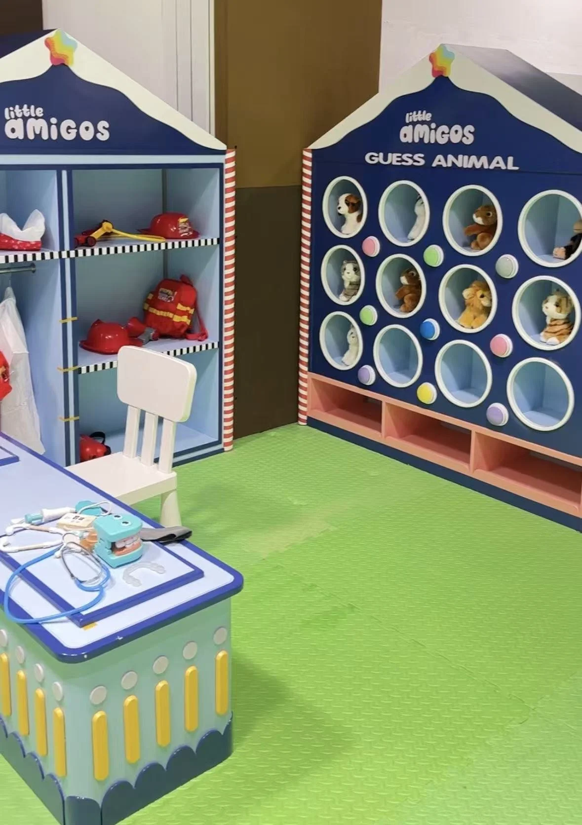 Playroom with toy shelves, medical toy set on table, and a guessing game with stuffed animals.