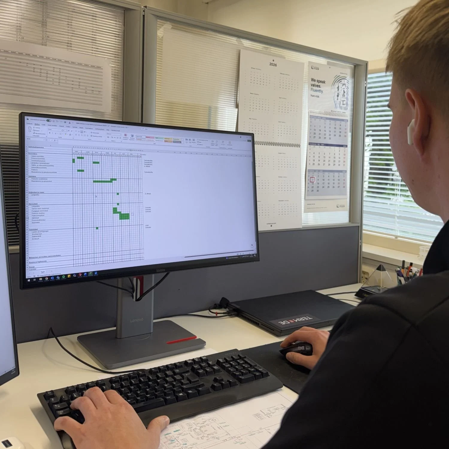 Työntekijä tietokoneella, näytöllä projektinhallintaohjelmisto.