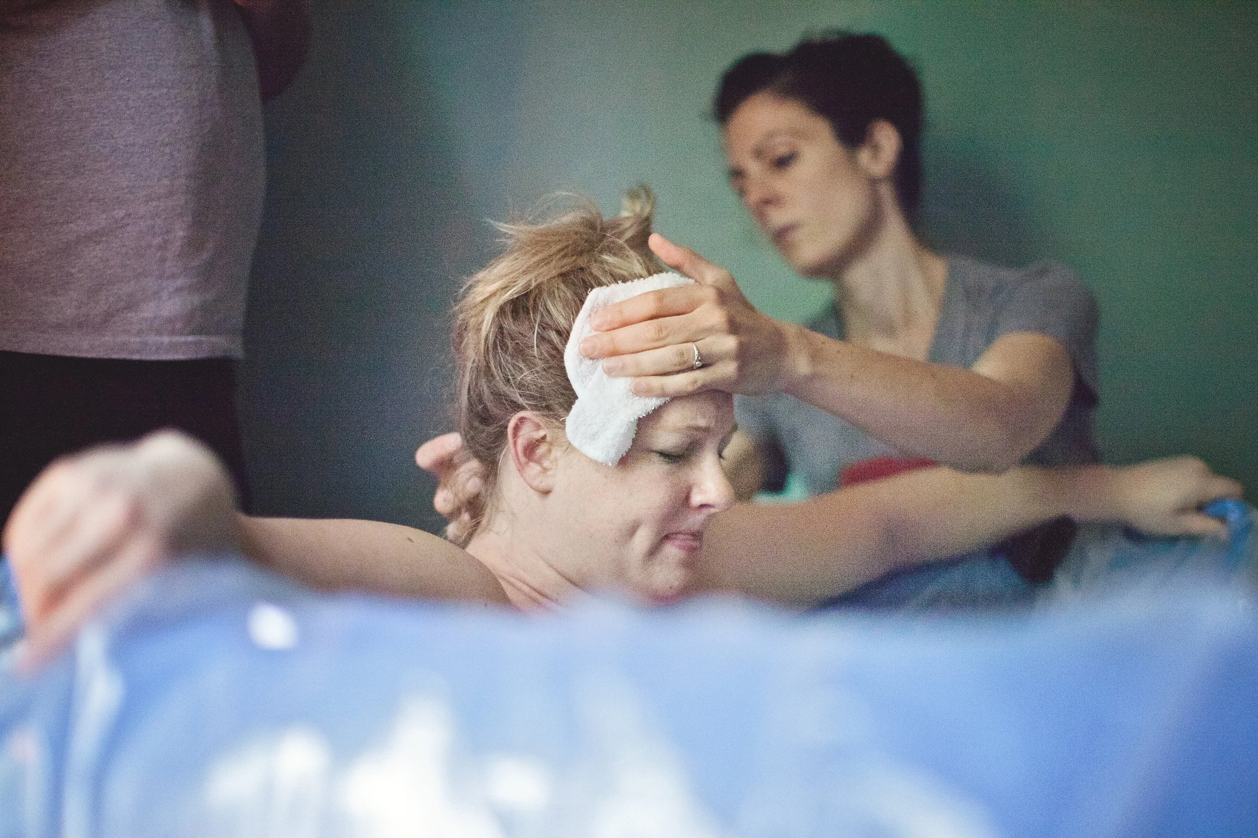 Woman in labor in a hydrotherapy tub with the support of a doula helping her through her waterbirth.
