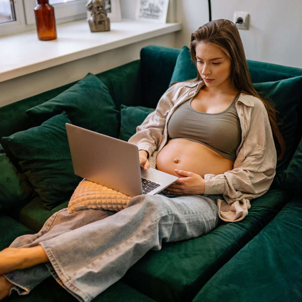 Close-up of a pregnant woman with a computer sitting on a couch