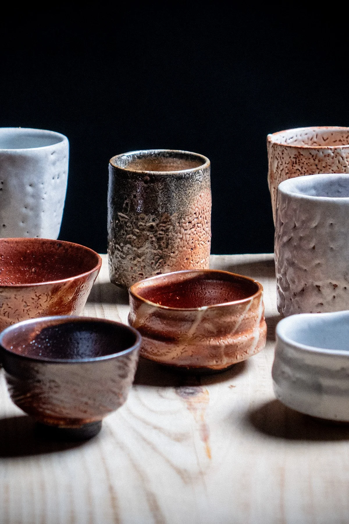 Handmade cups with Shino glaze featuring crackled textures and soft atmospheric surfaces.
