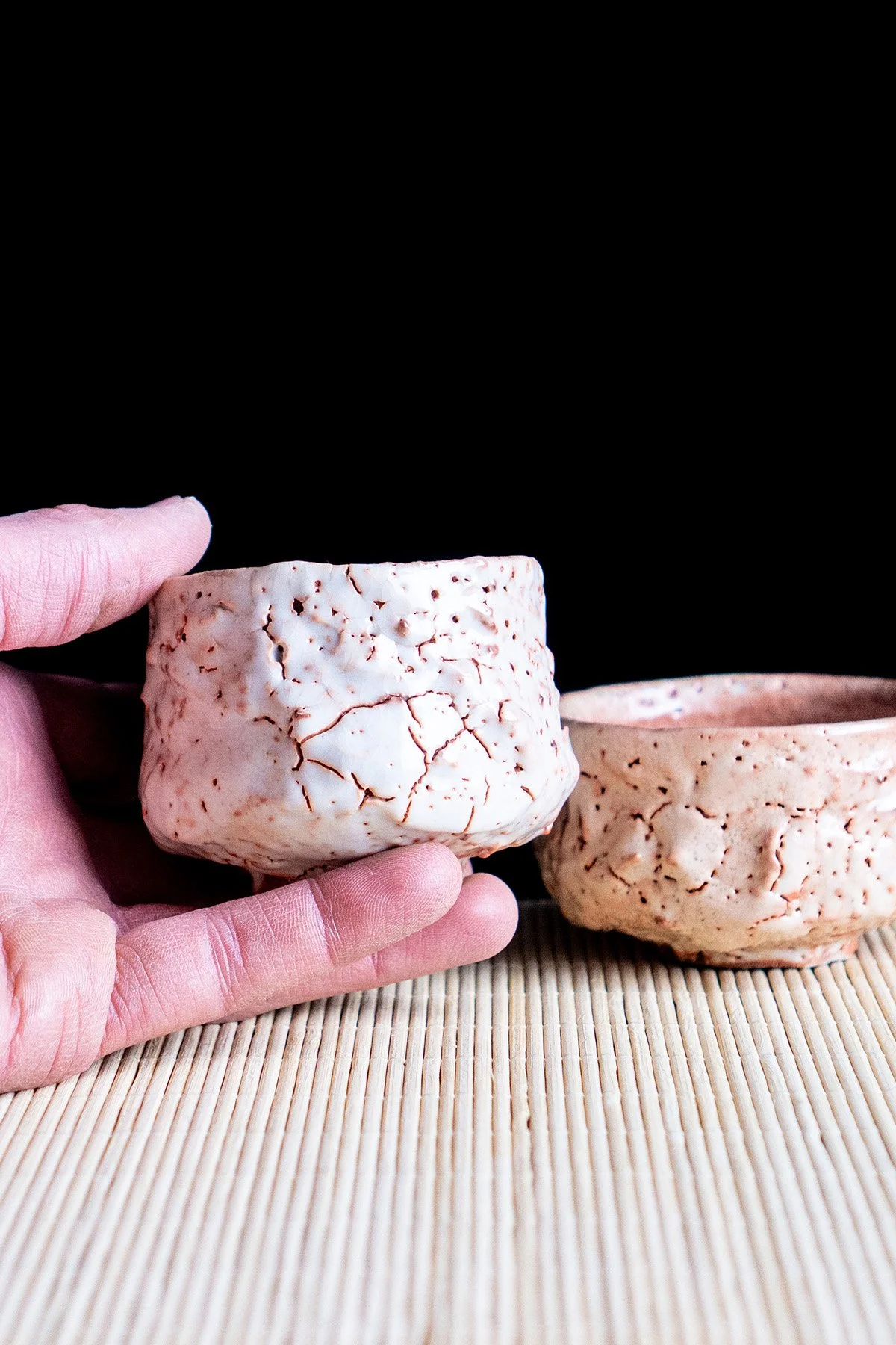 Small handmade sake cups with expressive Shino glaze surfaces shaped by fire and reduction firing.