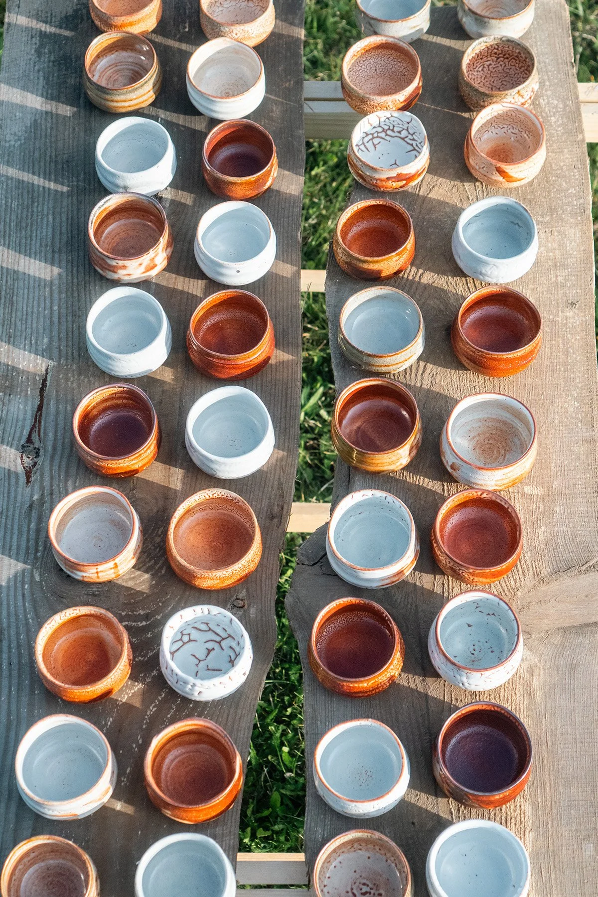 Small handmade sake cups with expressive Shino glaze surfaces shaped by fire and reduction firing.
