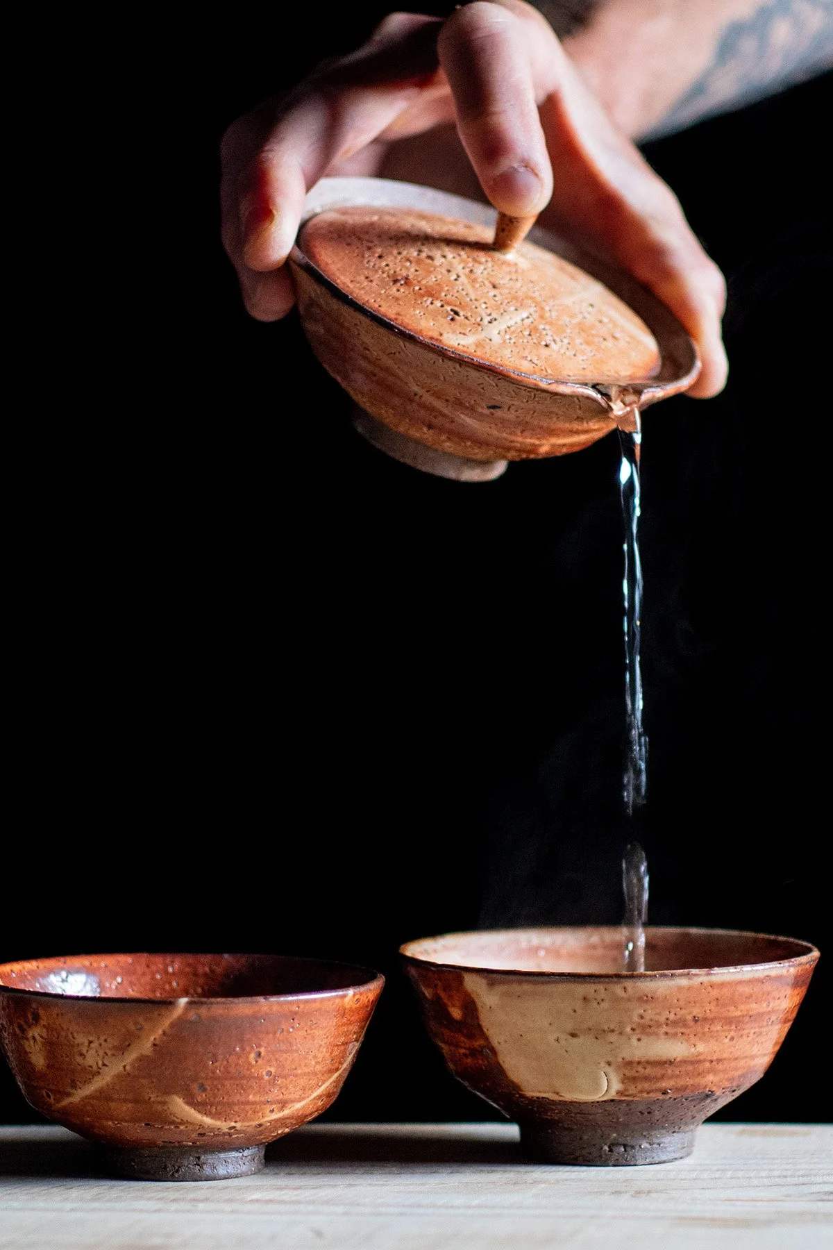 Pouring tea from a wide Shiboridashi teapot into handmade ceramic cups during a quiet daily tea ritual.