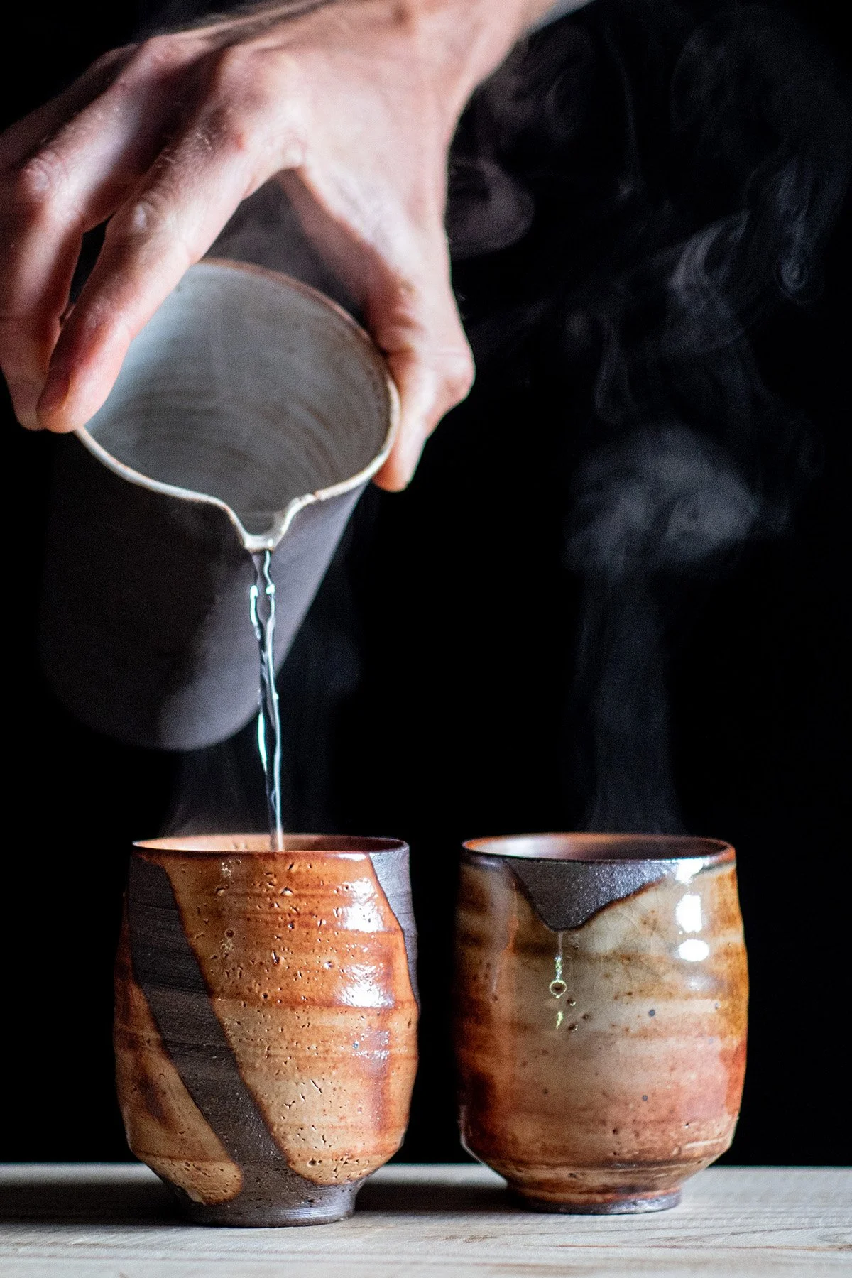 Pouring tea from a Chahai into handmade ceramic cups during a quiet daily tea ritual.