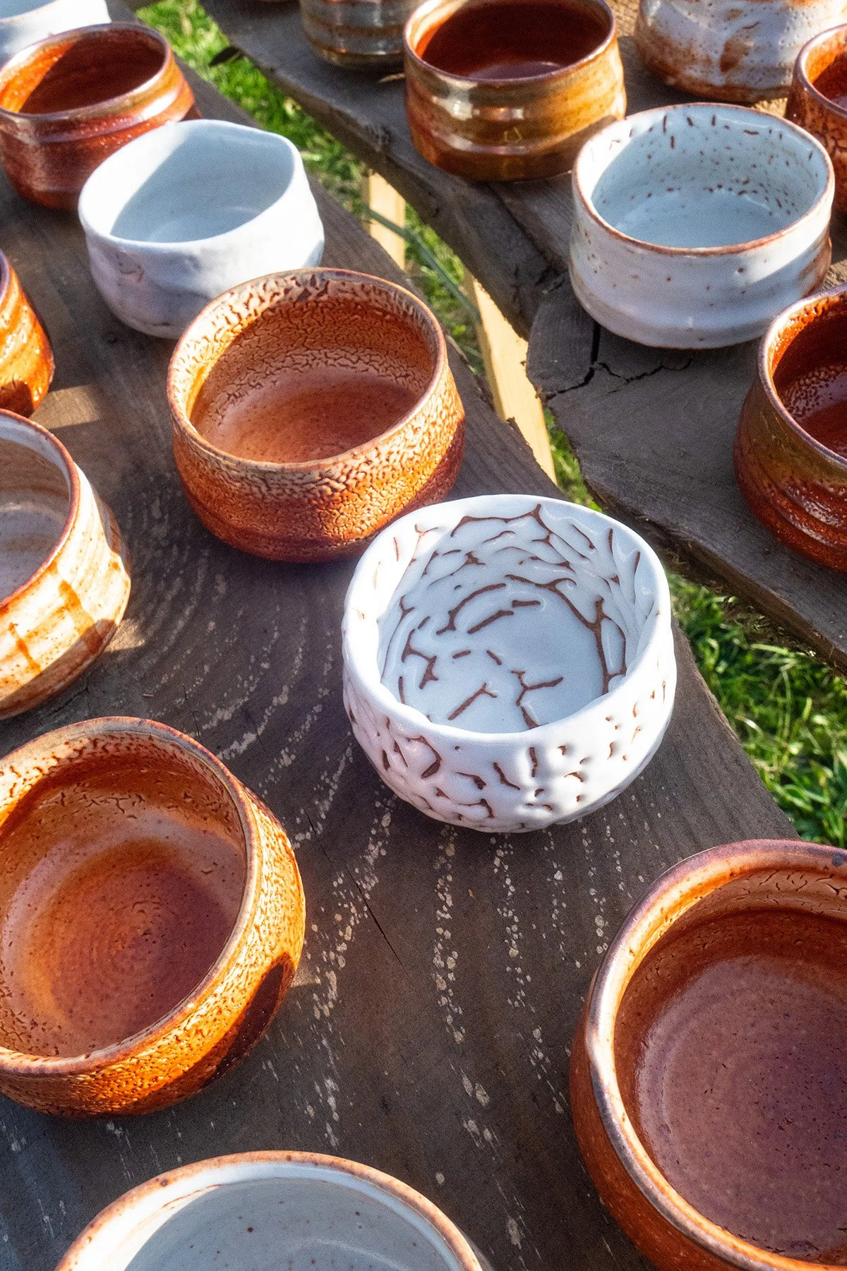 Small handmade sake cups with expressive Shino glaze surfaces shaped by fire and reduction firing.