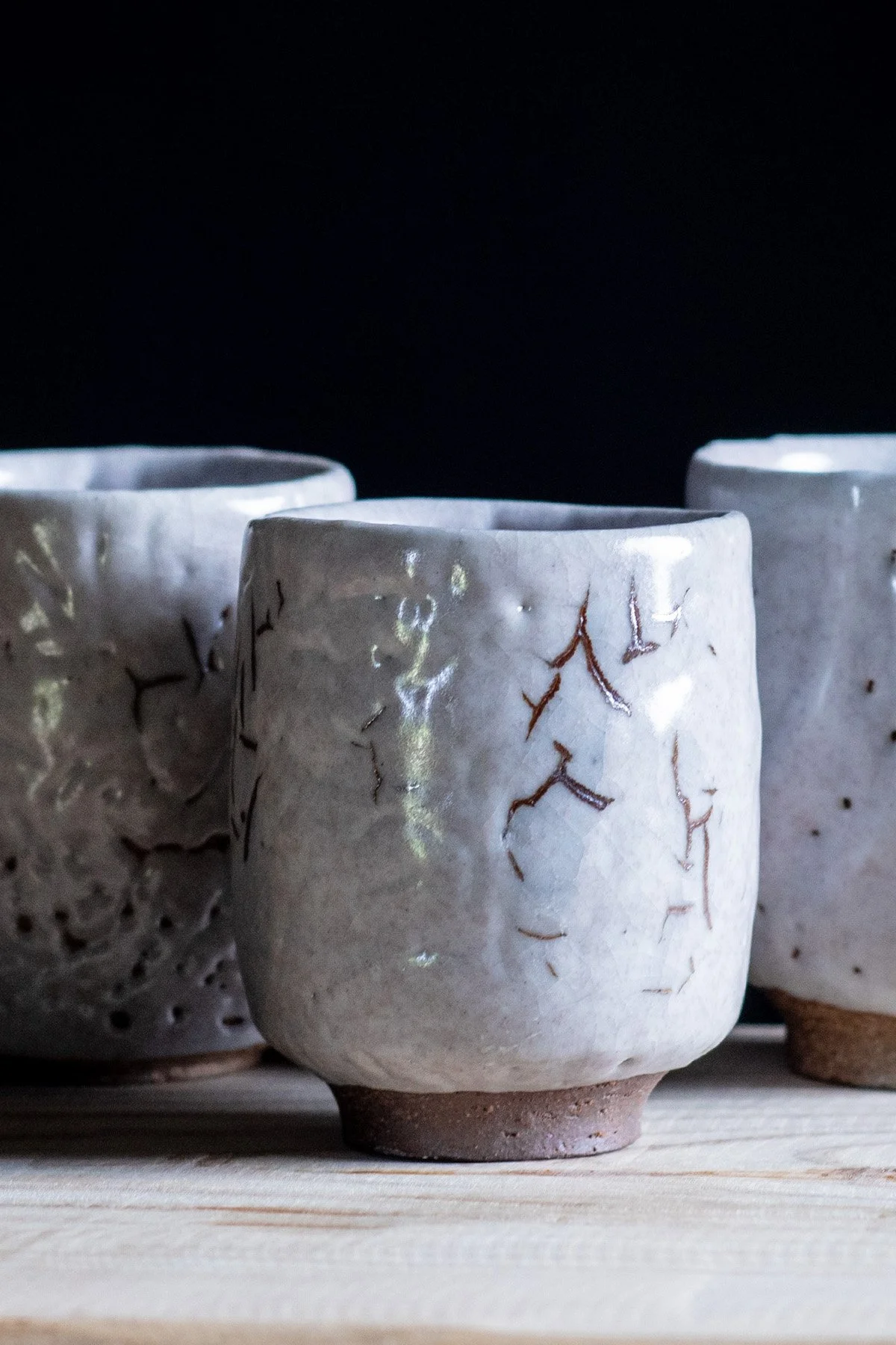 Handmade yunomi cups with Shino glaze featuring crackled textures and soft atmospheric surfaces.