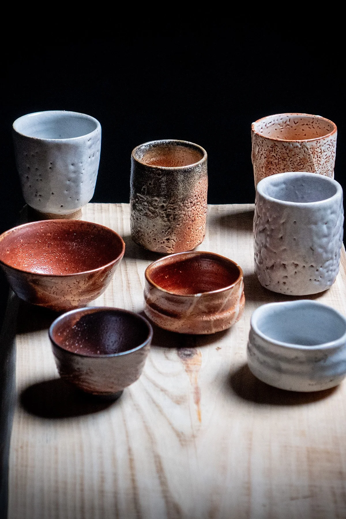 Handmade cups with Shino glaze featuring crackled textures and soft atmospheric surfaces.