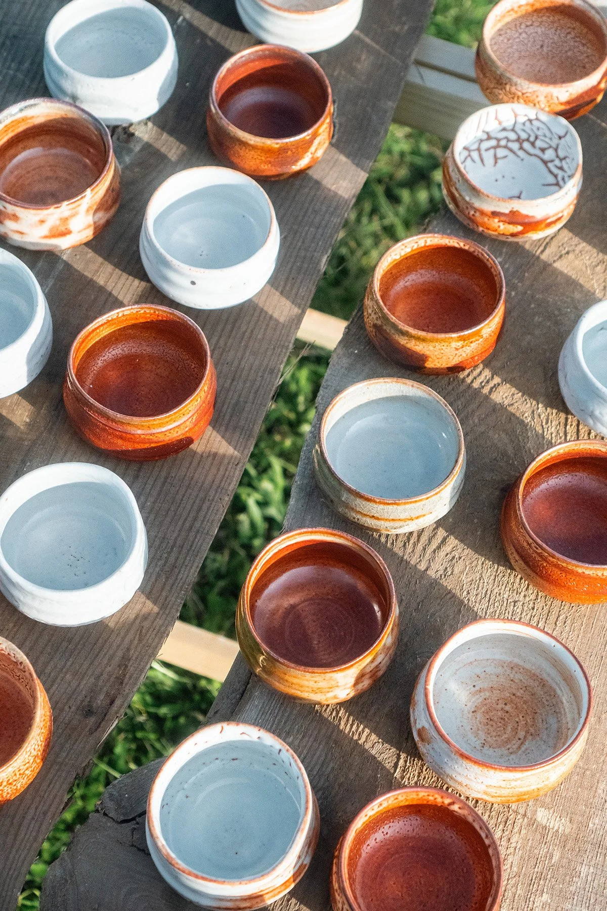 Small handmade sake cups with expressive Shino glaze surfaces shaped by fire and reduction firing.