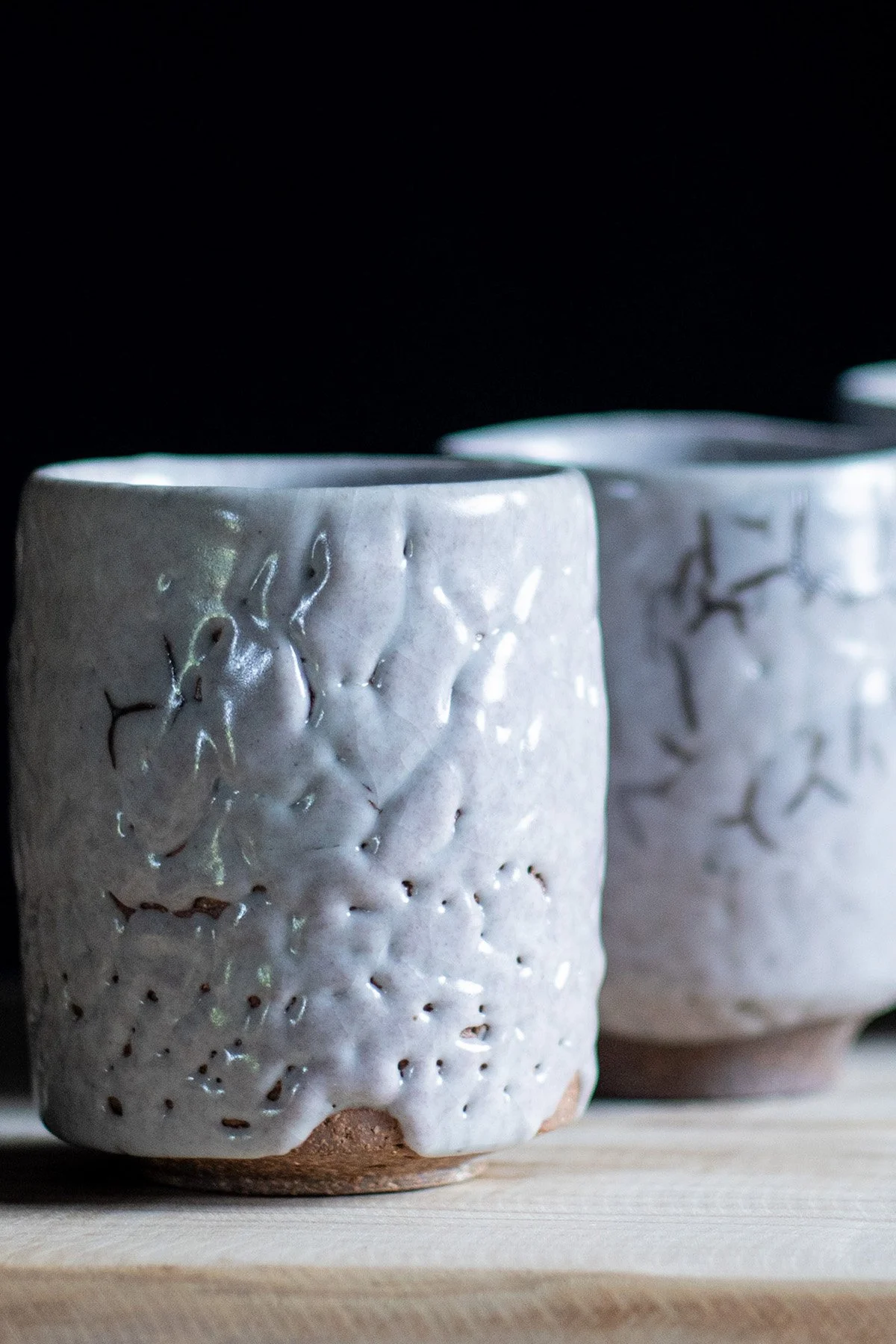 Handmade yunomi cups with Shino glaze featuring crackled textures and soft atmospheric surfaces.
